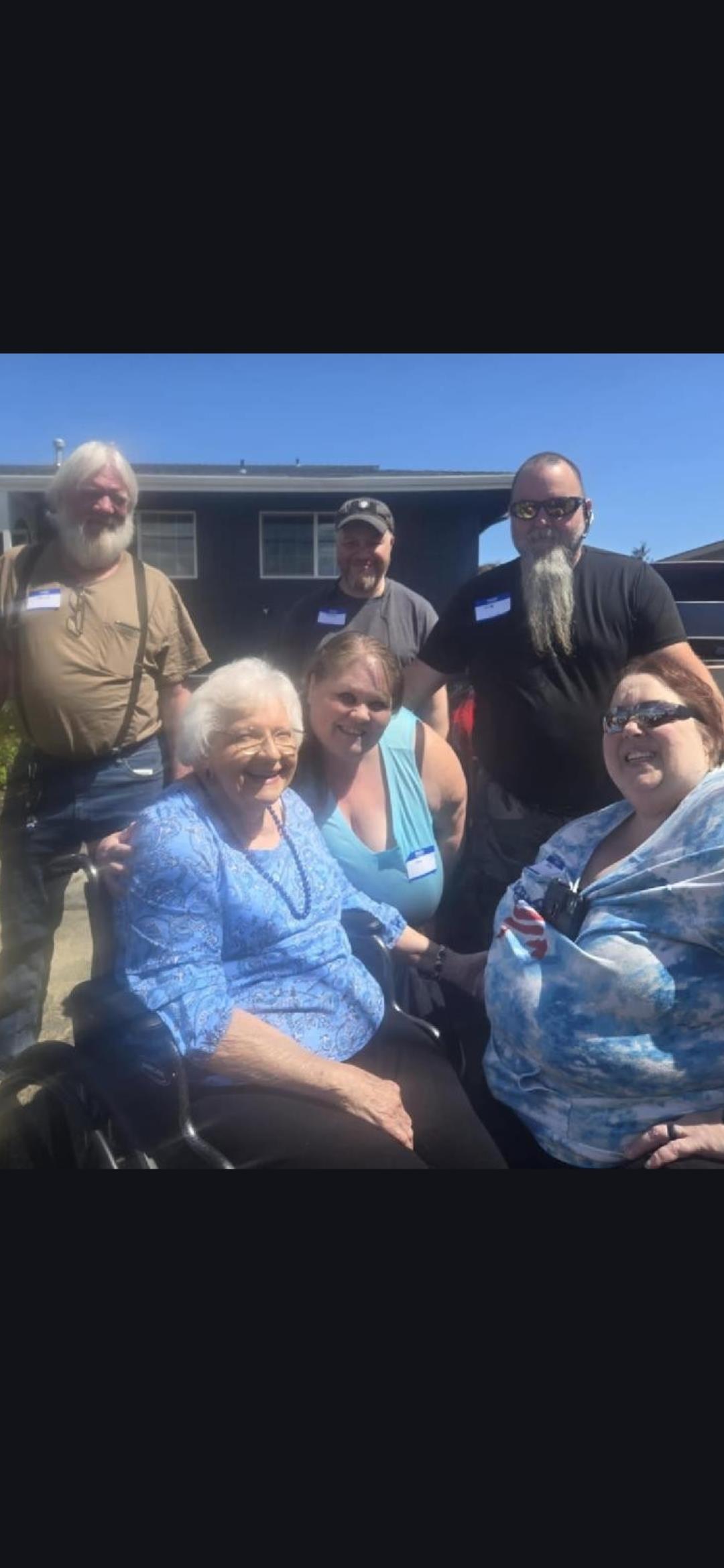 People enjoy a reunion outside a house on a sunny day, sharing smiles and laughter together.