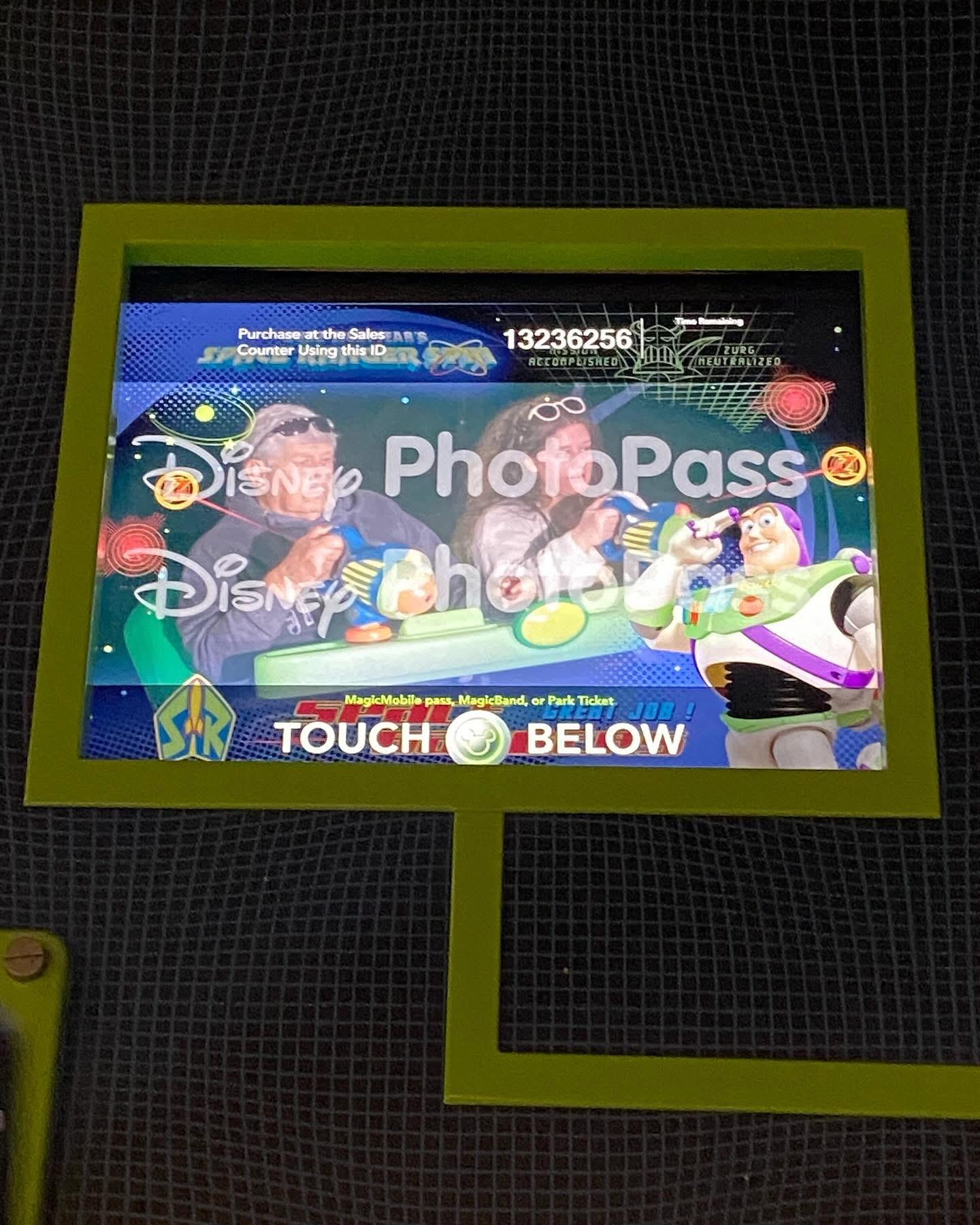Guests interact with a display that offers photo pass information at a Disney theme park.