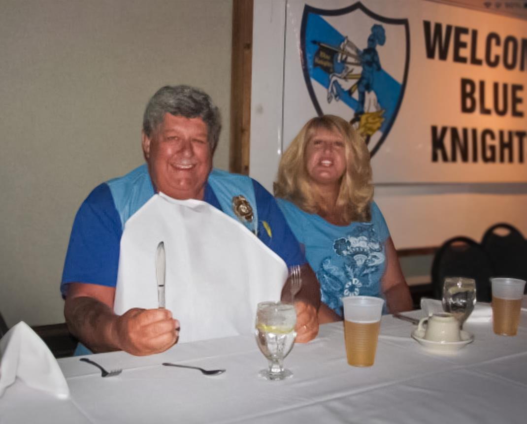 Two people sit at a table smiling while preparing for a meal in a restaurant setting.