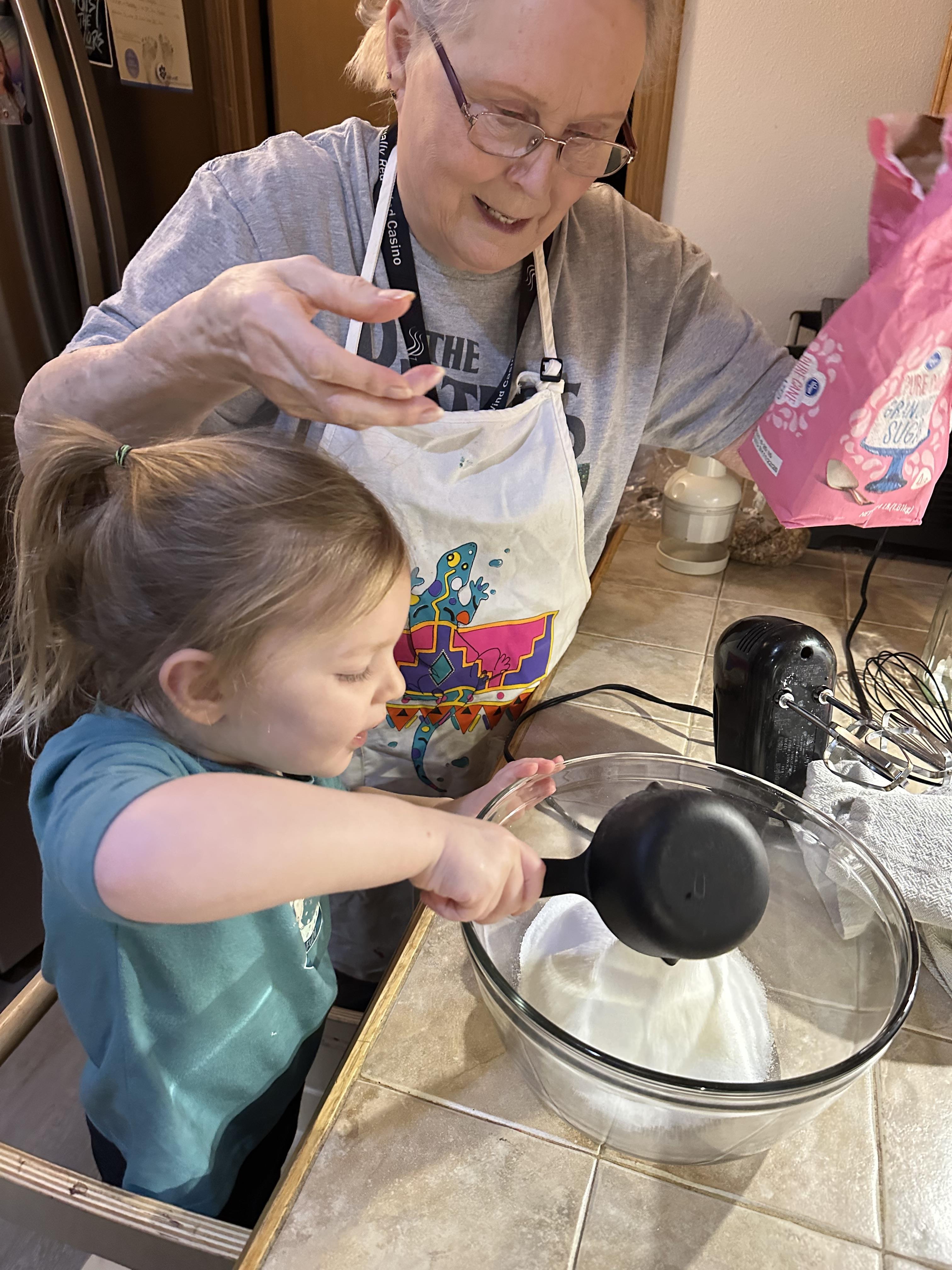 A woman and a child mix ingredients in a bowl during a baking session in a kitchen.