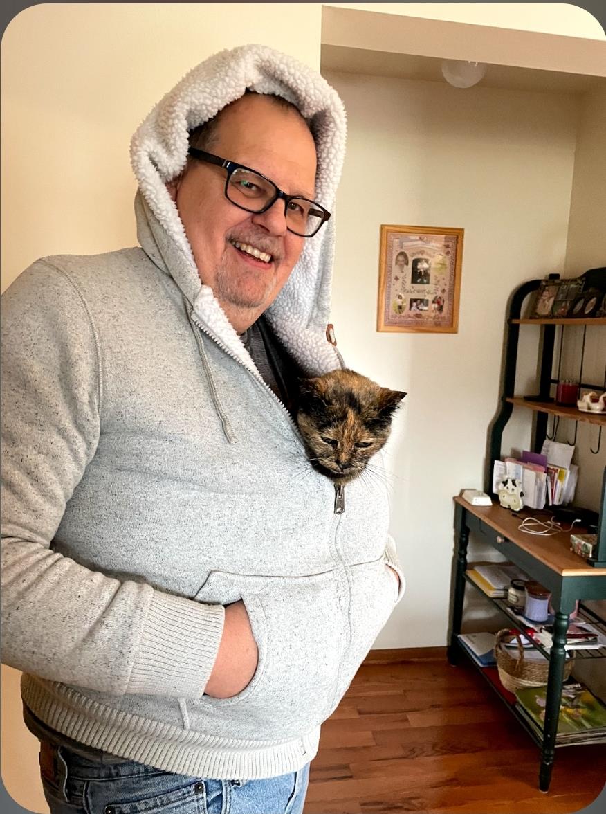 A man wearing a hoodie with a cat in his pocket