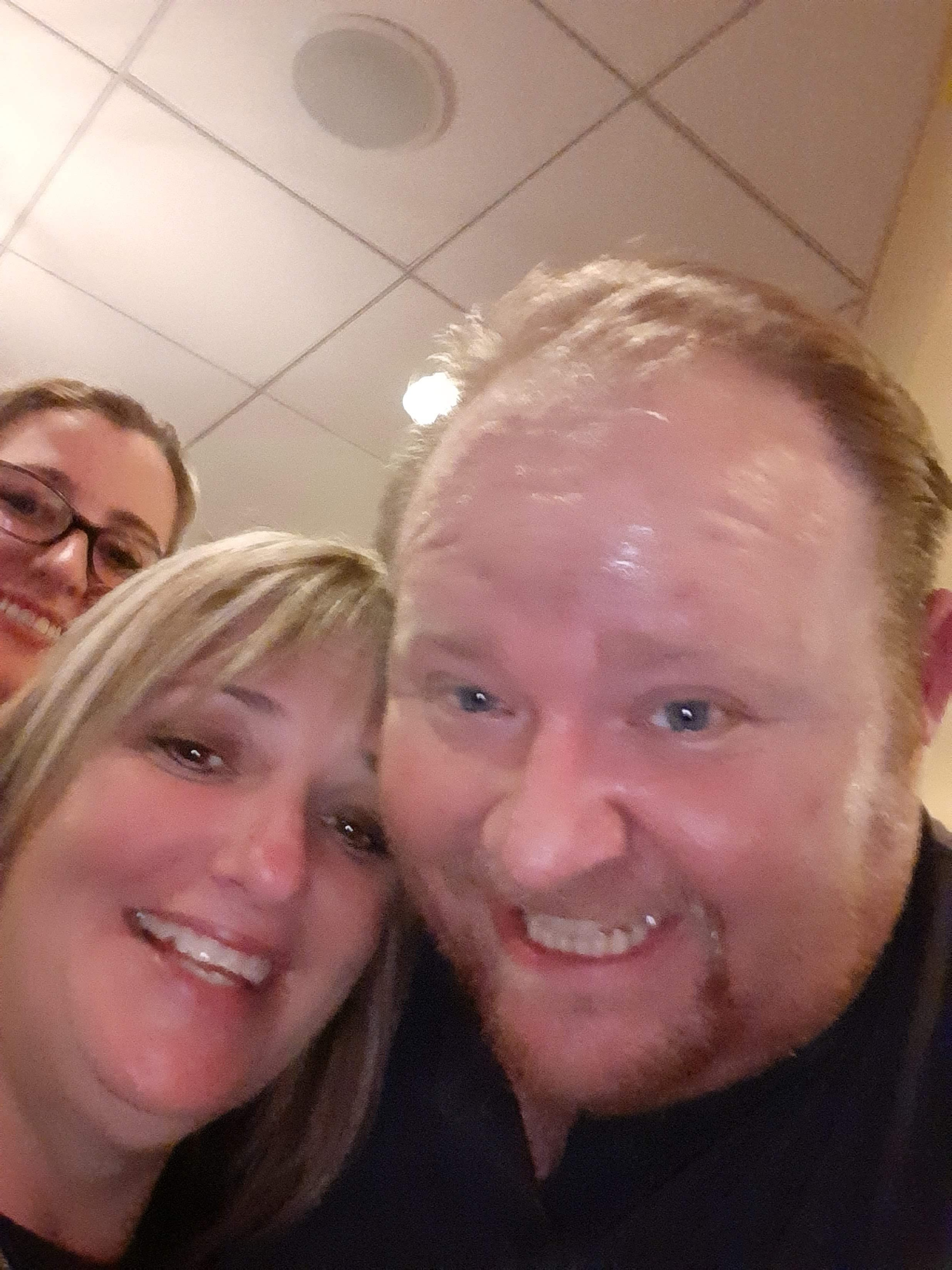 Three people enjoy a moment together, posing happily at a restaurant during a social event.