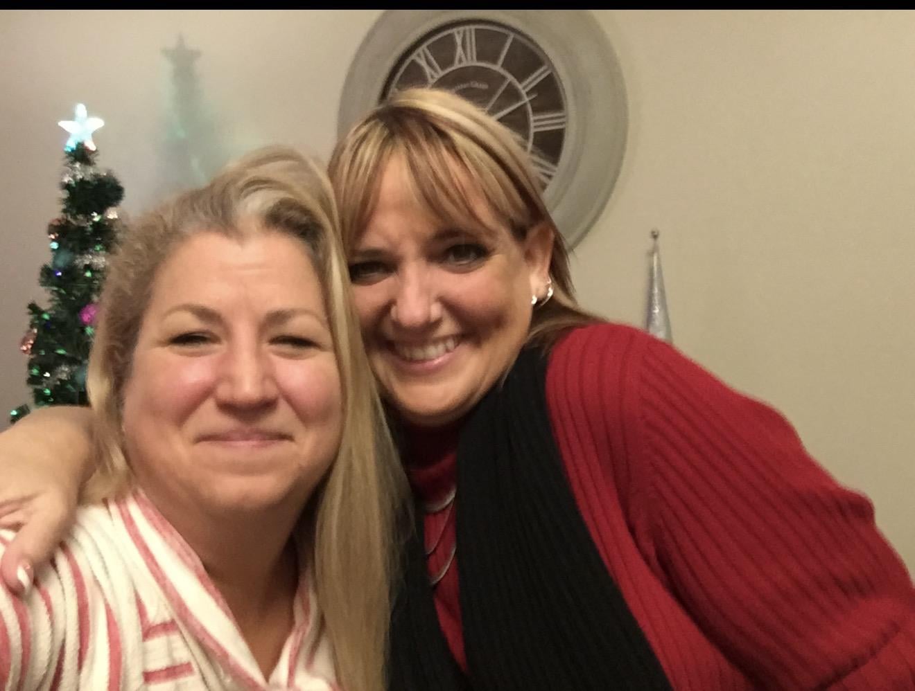 Two friends pose happily together while enjoying their time at a social gathering in the evening.