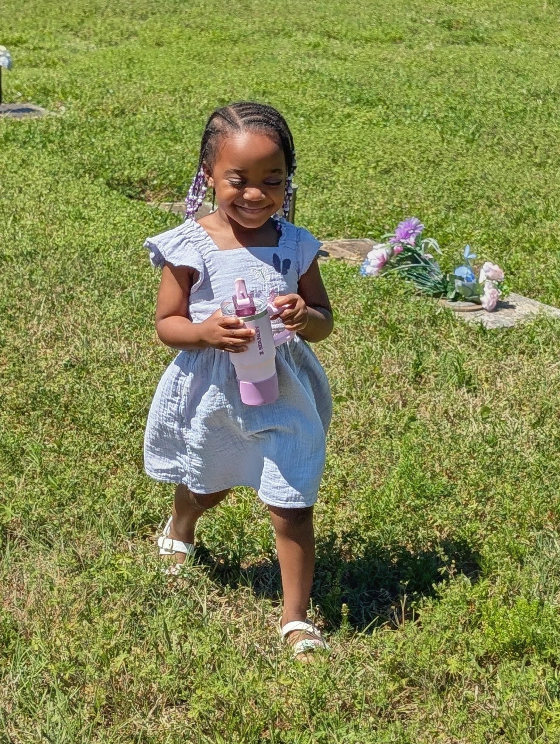 A girl in a dress holding a bottle