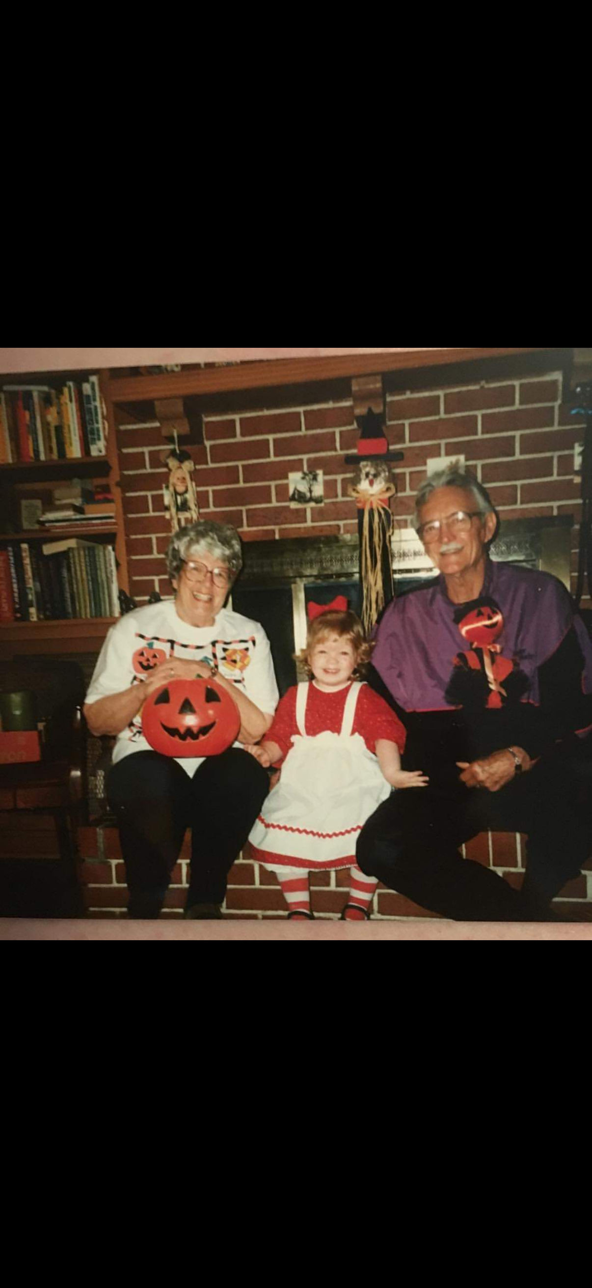 Three people sit together in a cozy living room during Halloween, smiling and enjoying the moment.