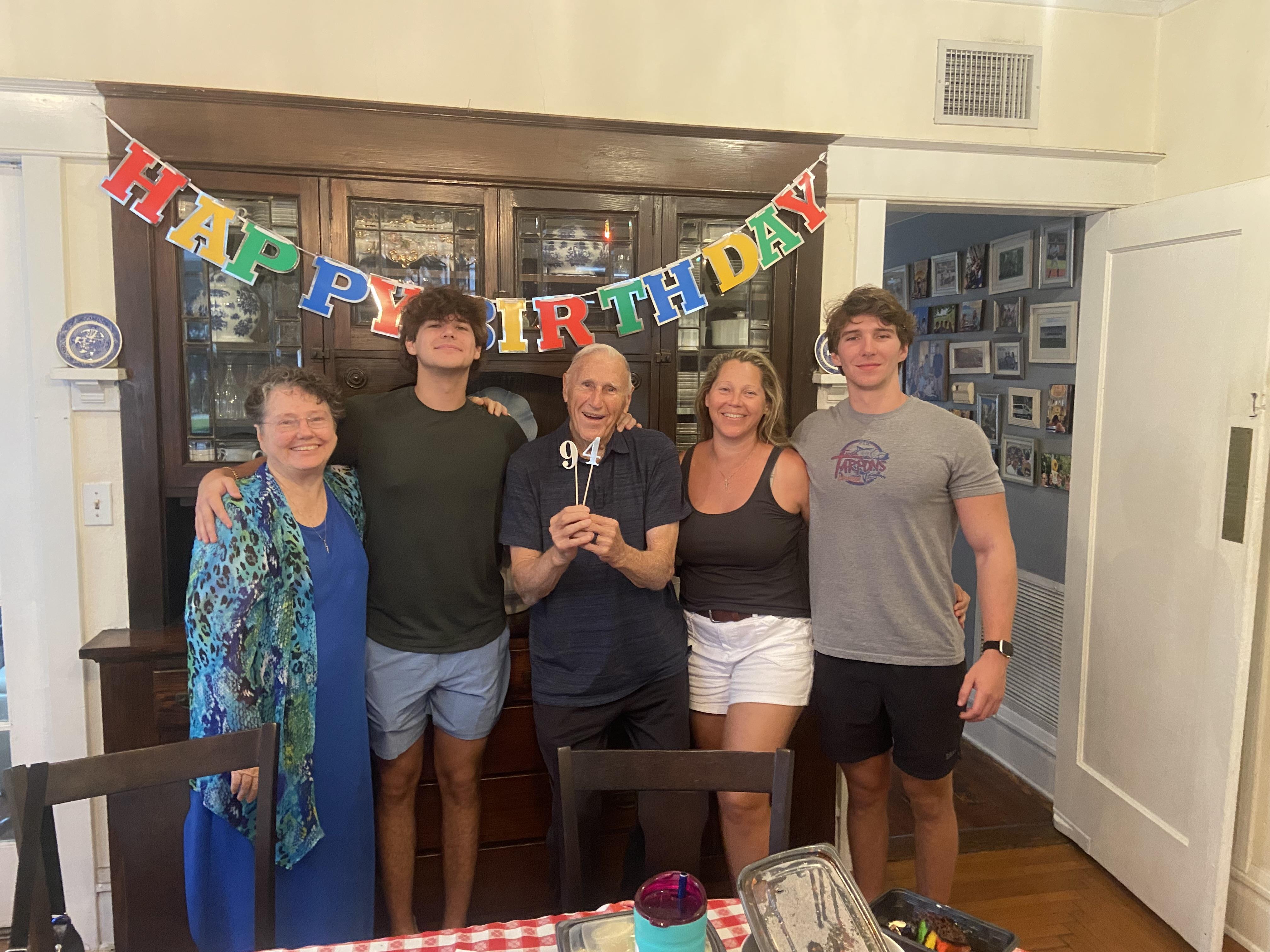 Family gathers together to celebrate a birthday with cake and smiles at a home setting.