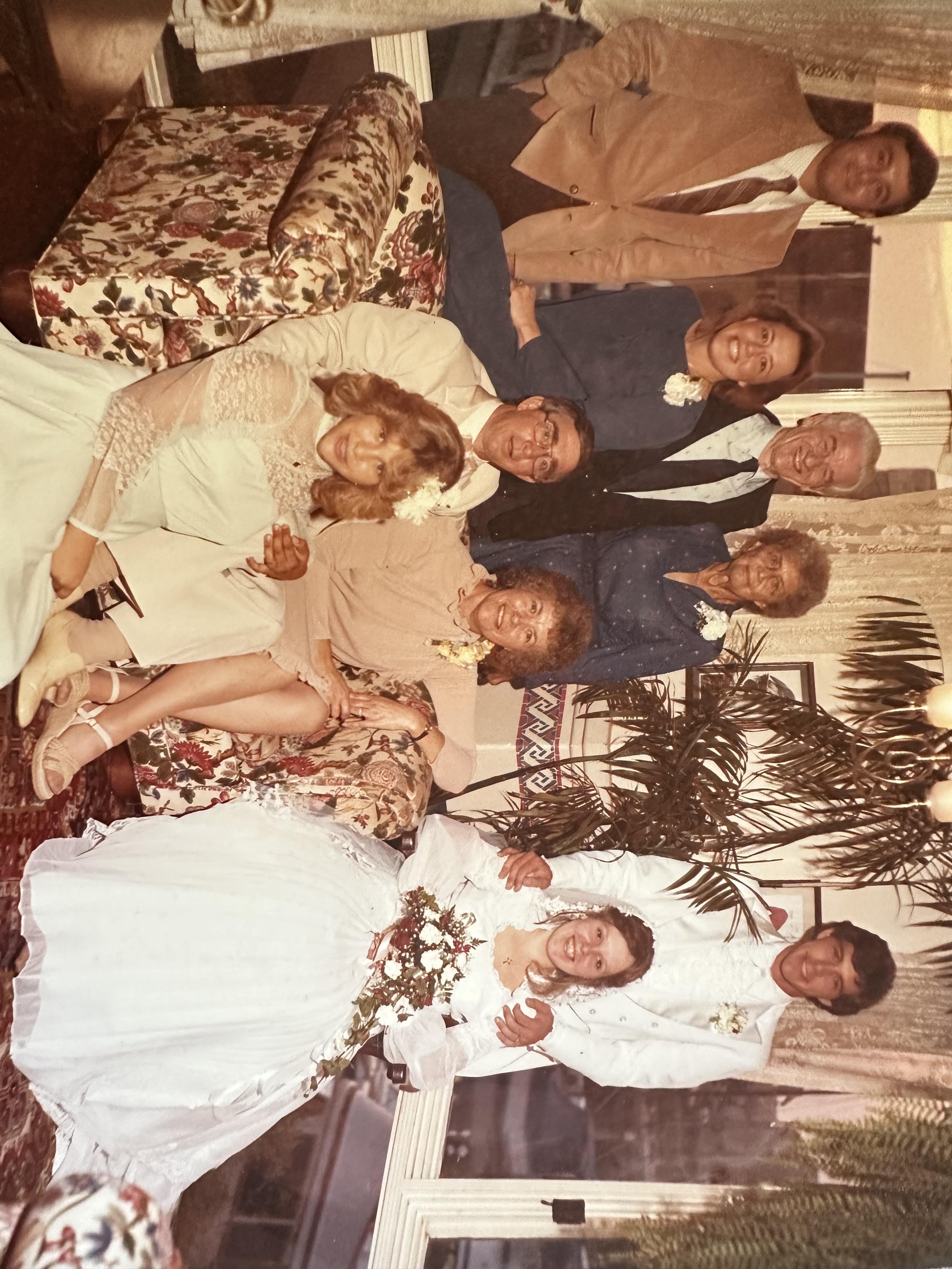 Group of family and friends gather to celebrate a wedding in a cozy living room scene.
