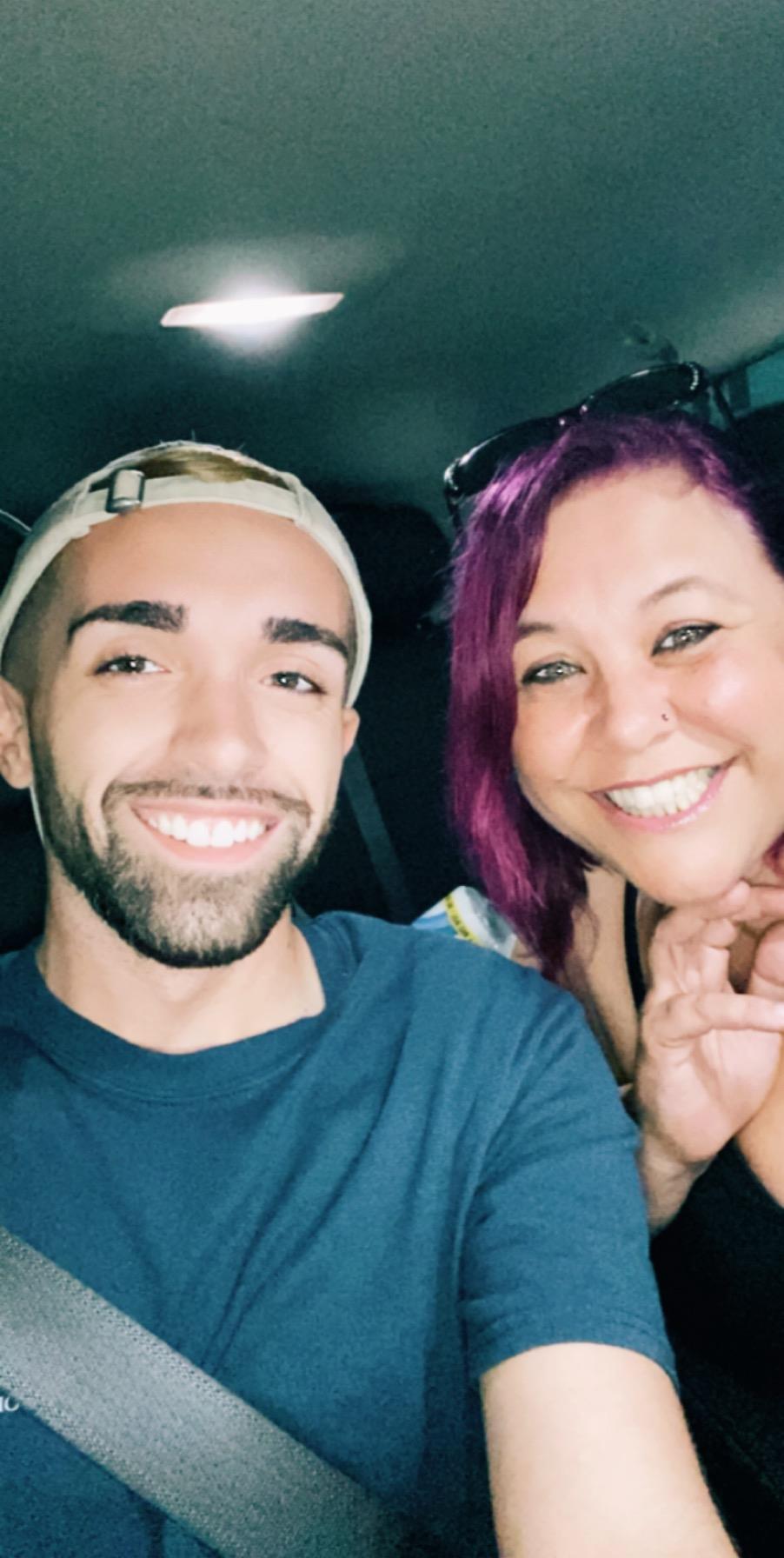 Two people take a selfie in a car, showing their smiles and enjoying the moment together.