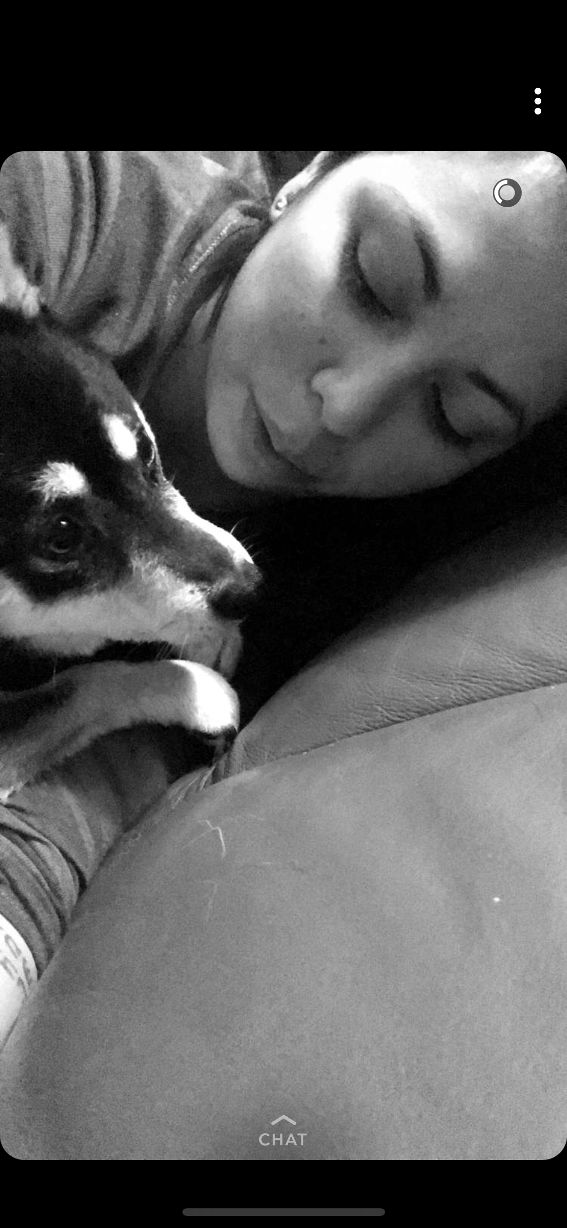 A person leans close to a dog on a couch. They enjoy a moment together during the evening.