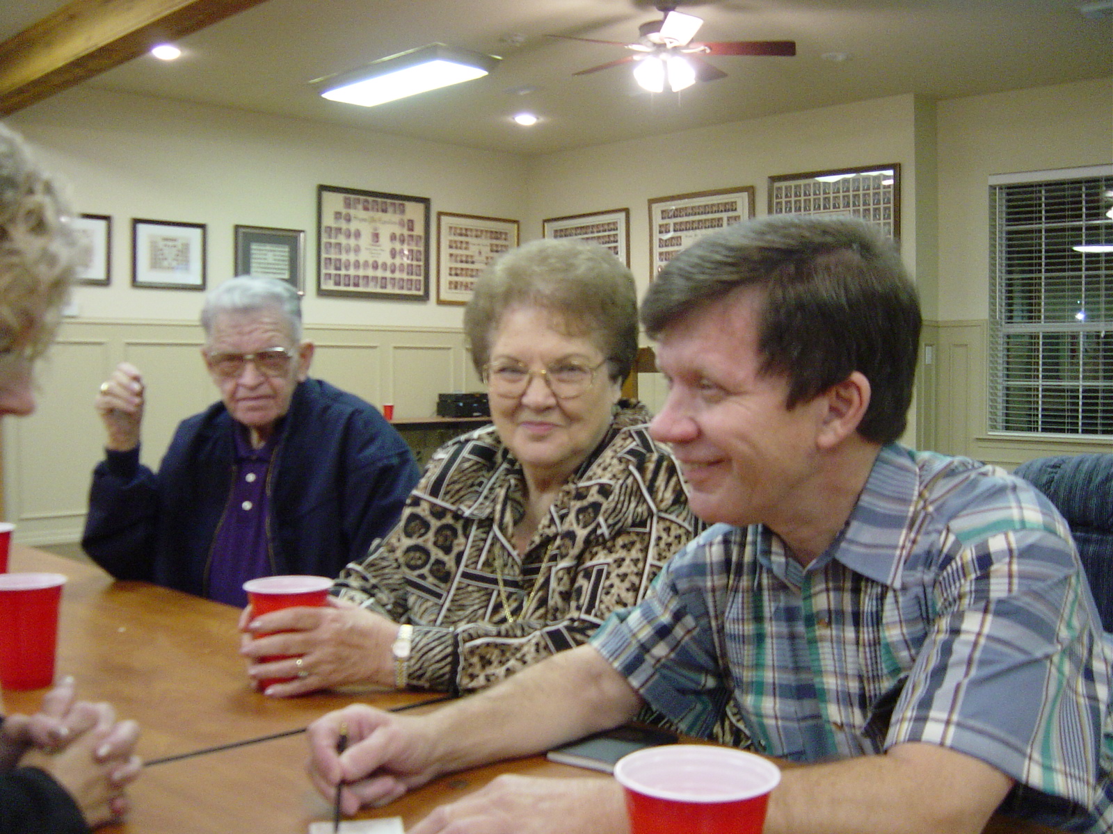 People sit together at a table with drinks, sharing stories and enjoying each other's company.