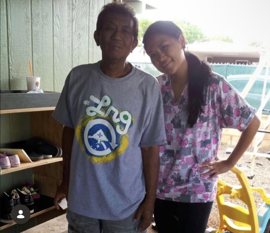 Two individuals stand close together, smiling in a relaxed environment where items are visible.