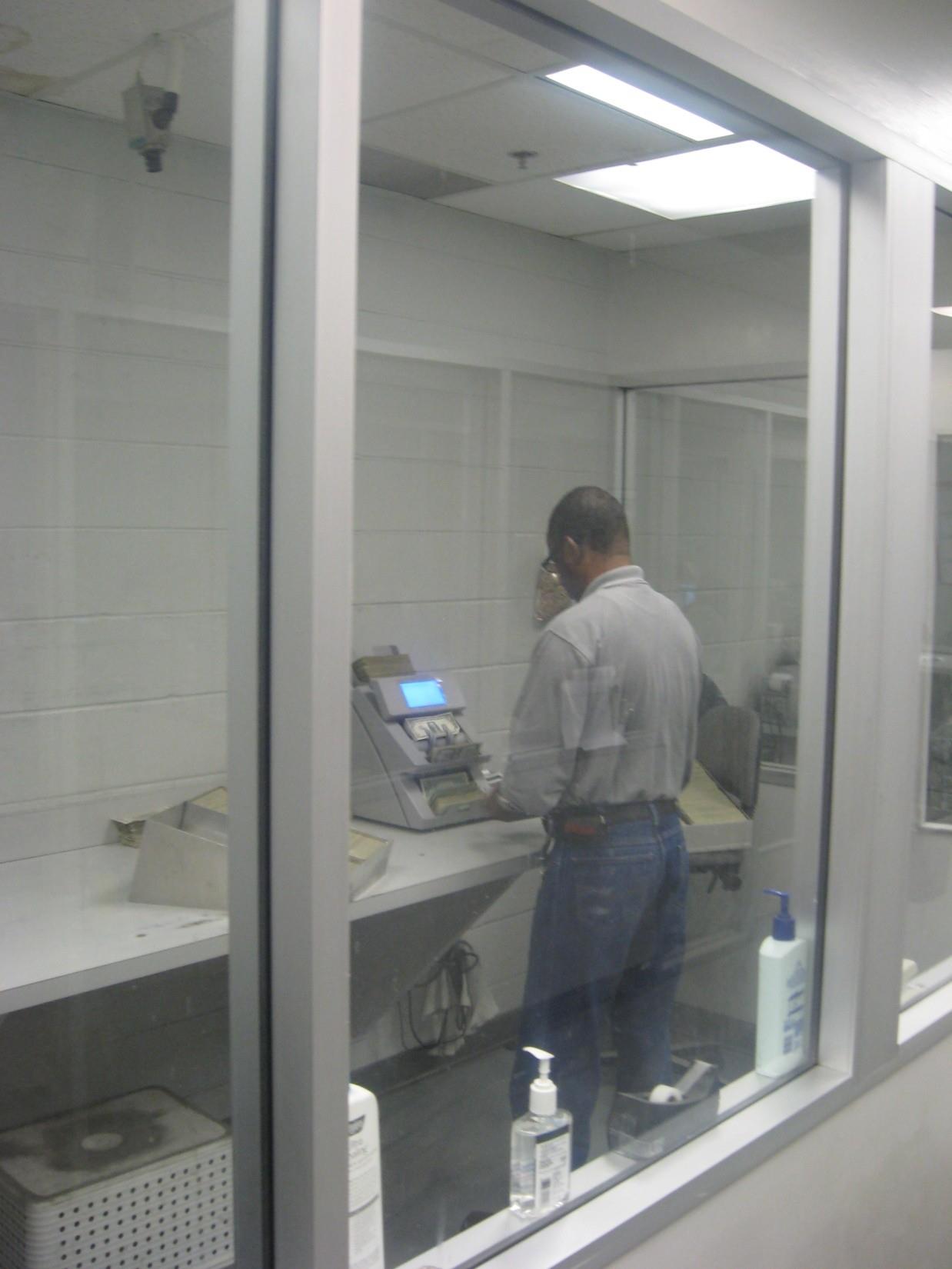 A person stands by a machine in a small room with a window, focusing on their task.