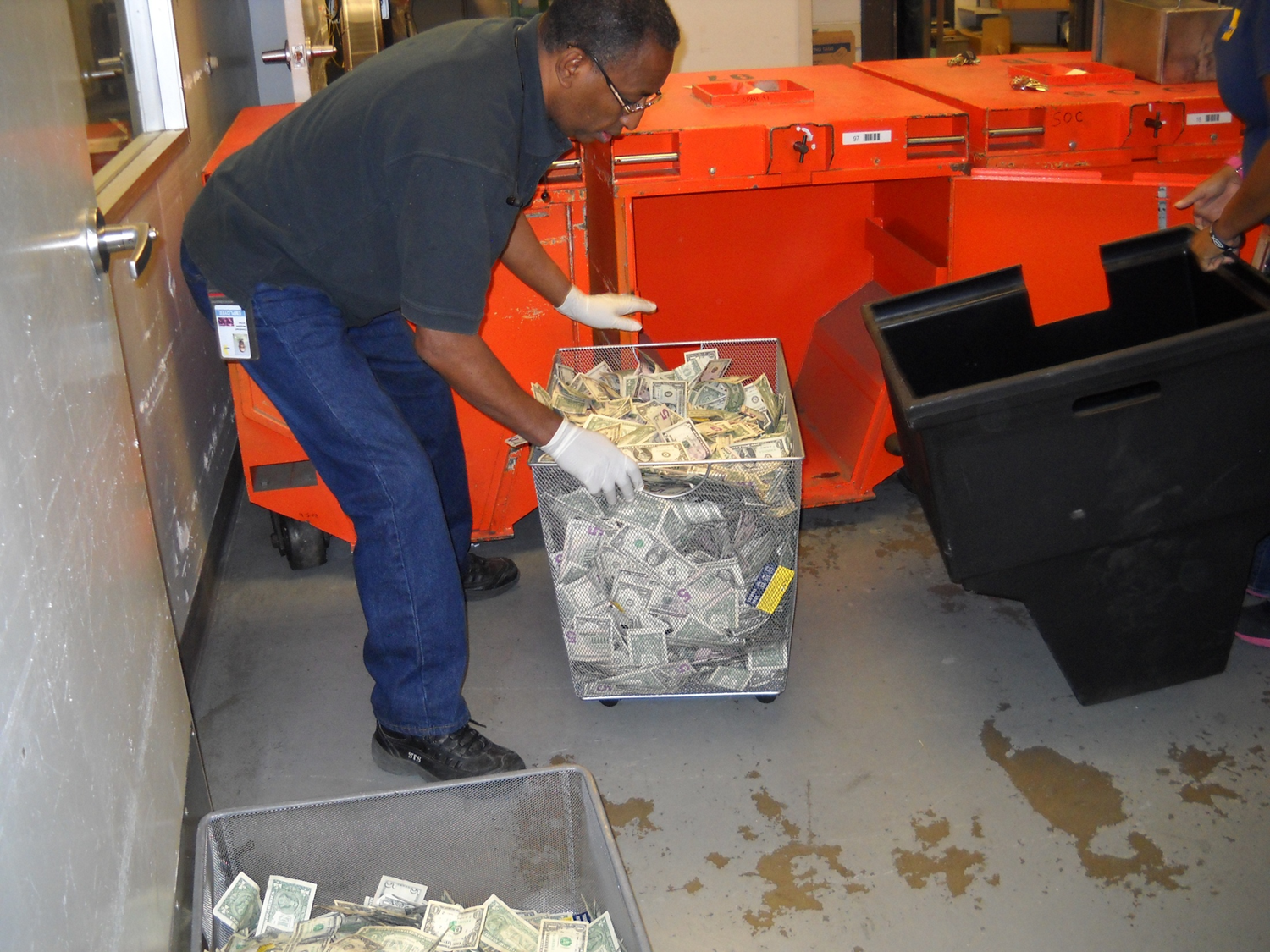 A worker takes out a bin filled with cash in a secure facility during an afternoon count.