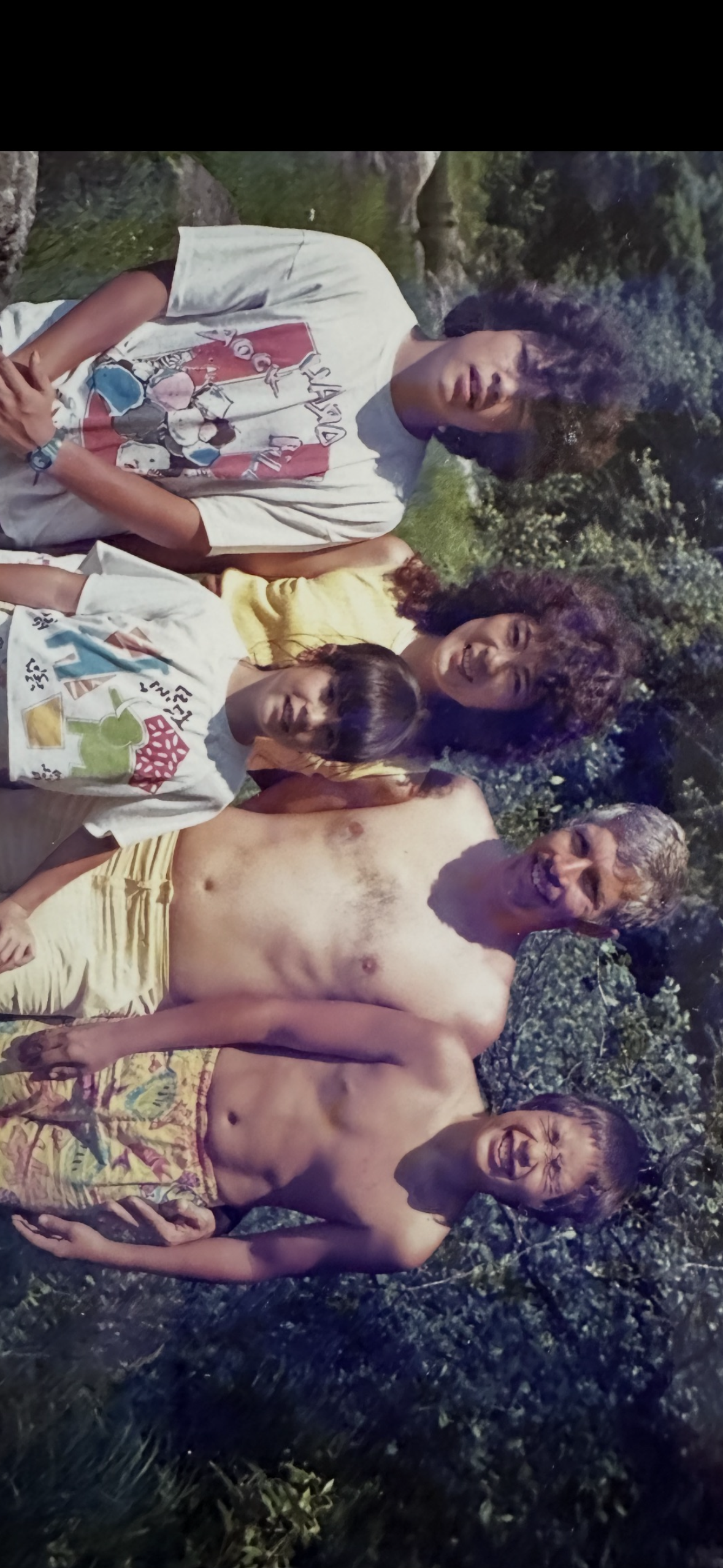 A group of adults and children stand in a garden smiling and posing for a picture during summer.