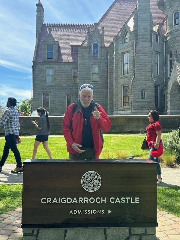 Groups of people visit Craigdarroch Castle in Victoria while one man poses for a photo.