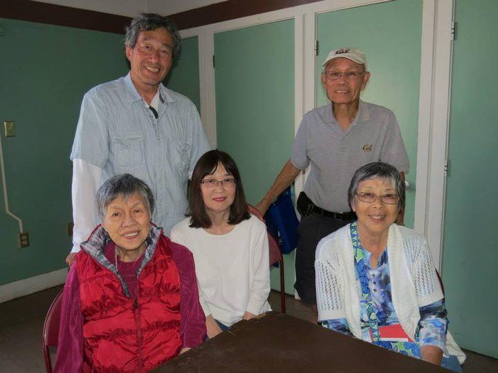 Five people are smiling together in a room, enjoying quality family time.