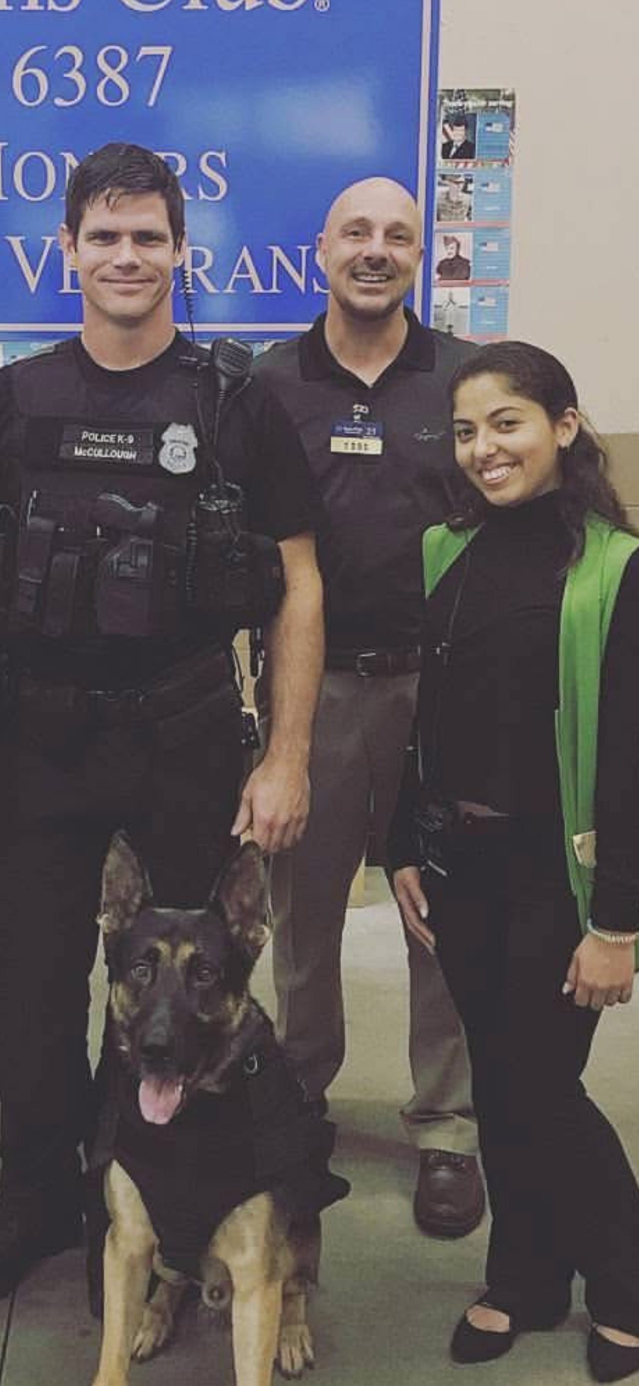 Police officers and a woman stand together with a police dog at a community gathering in a venue.
