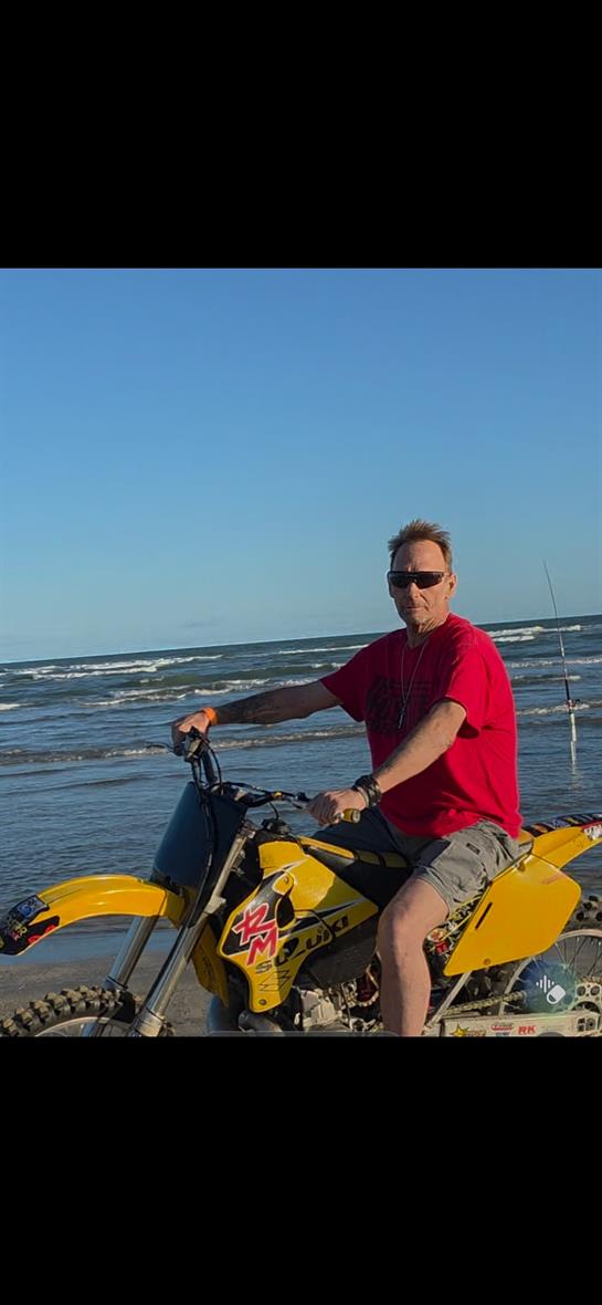 A man on a motorcycle on the beach