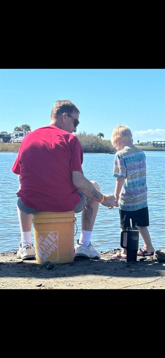 A man and boy sitting on a bucket by water