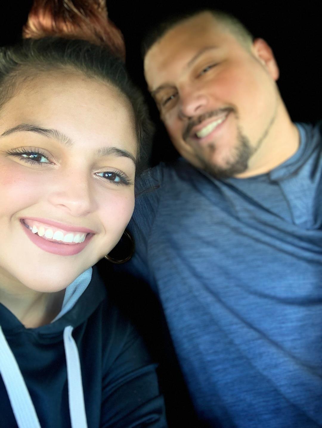Two people smile at the camera while sitting together in a car. They enjoy their time.