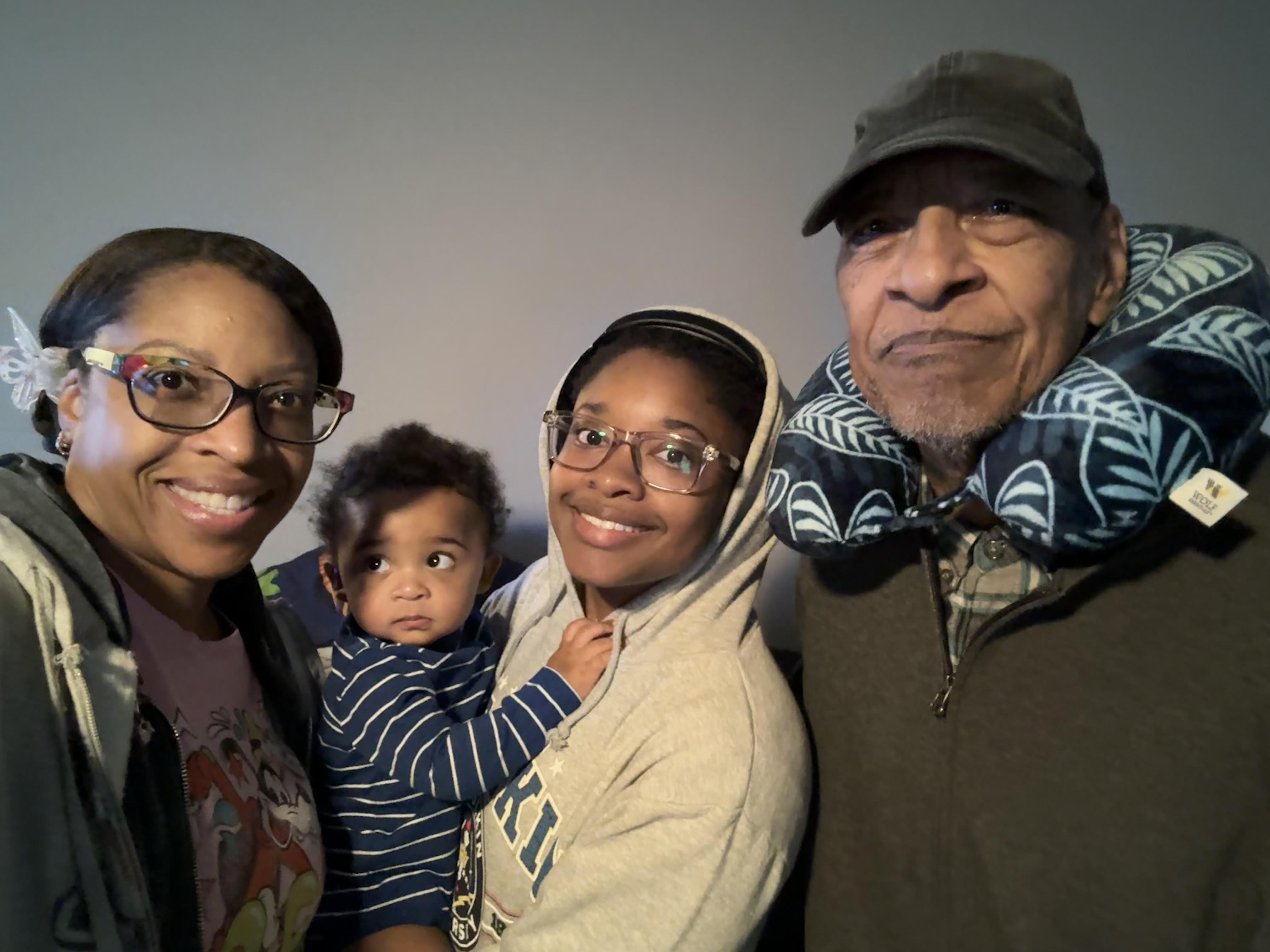 Four family members smile together for a picture in the living room.