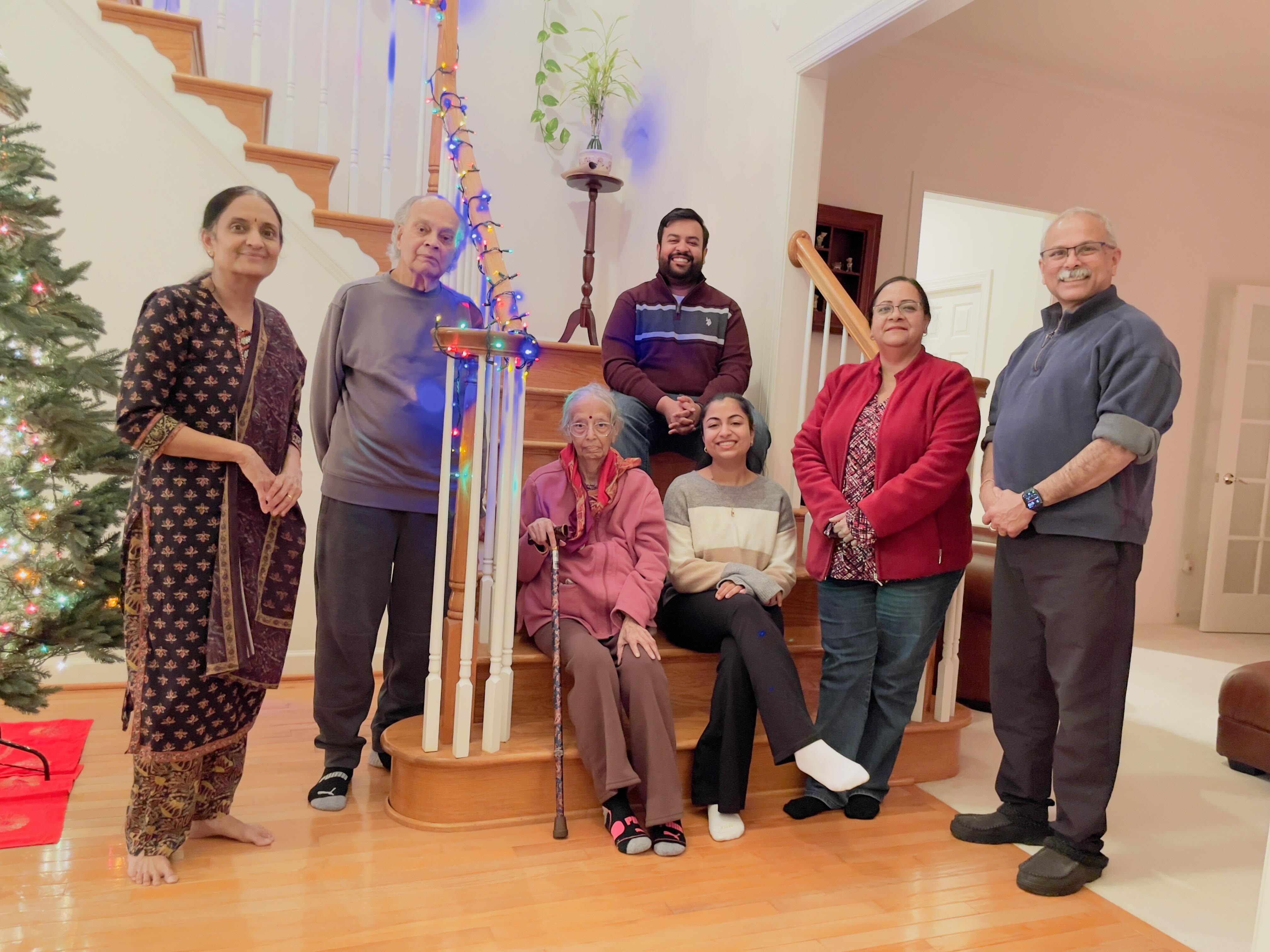 Seven diverse people smile together in a home, enjoying a special moment.