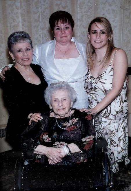 Four women of different ages pose together for a picture at a family gathering in a hall.