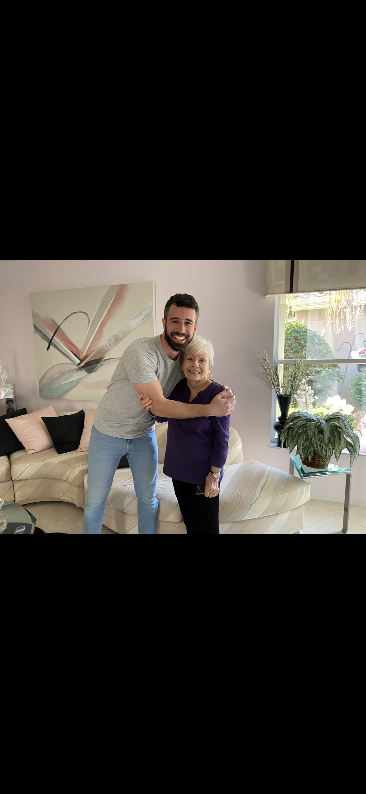 A man and a woman share a warm hug in a living room during a family visit at home.