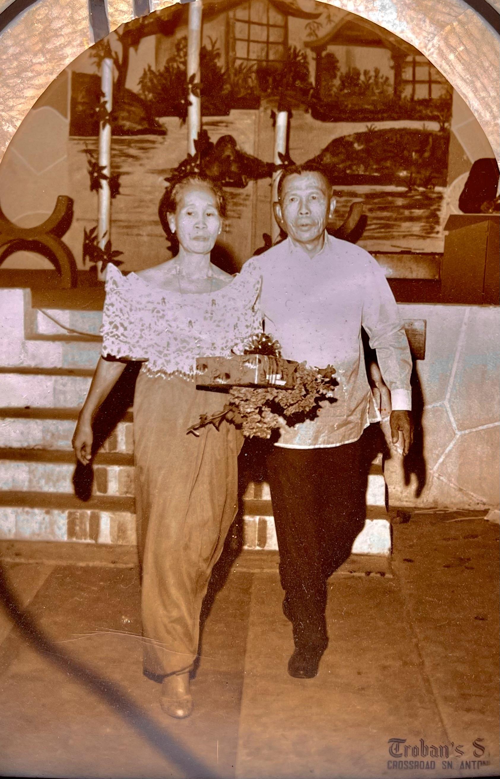 A man and woman walk side by side with a flower arrangement in their hands.