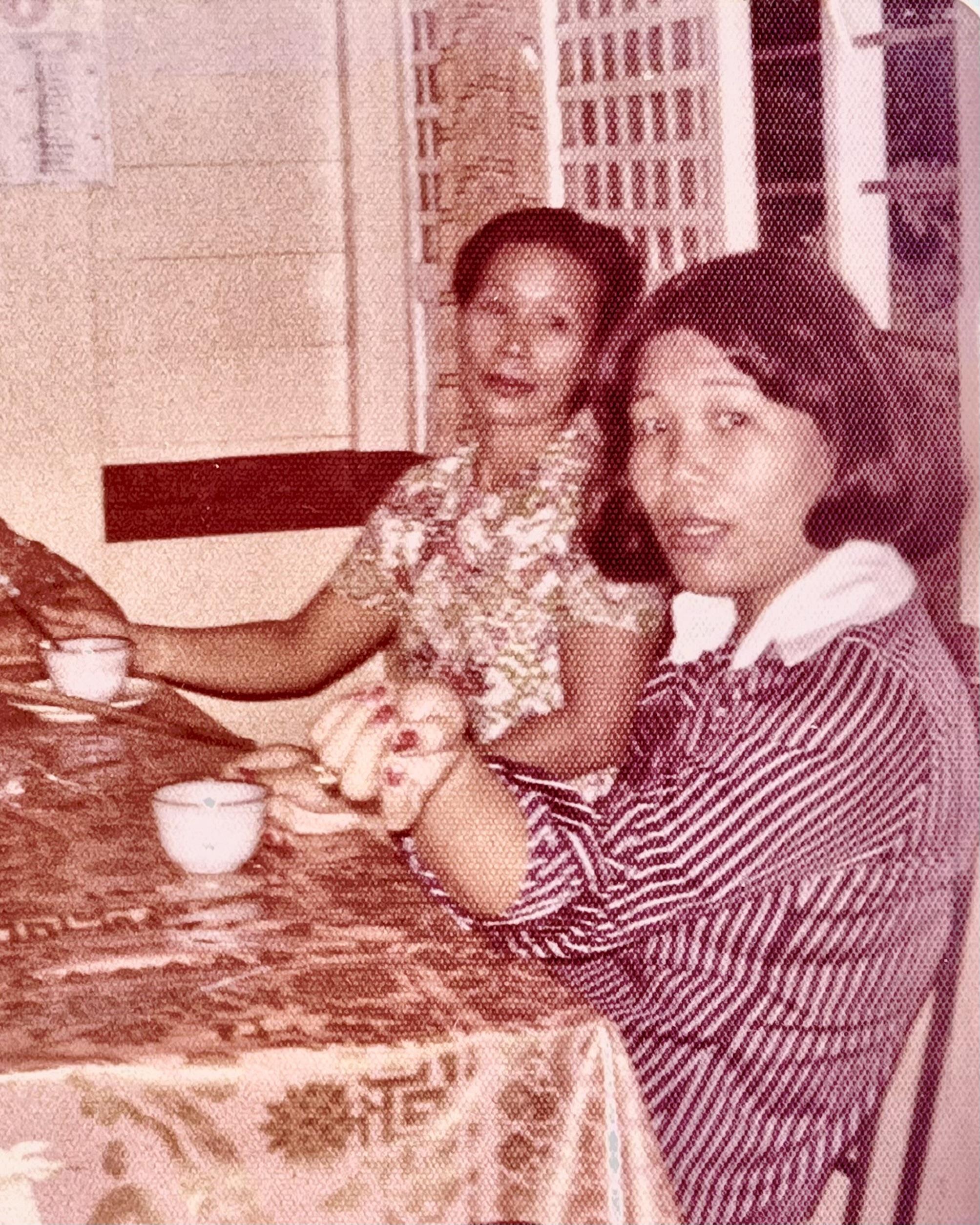 Two women sit together at a table enjoying tea while talking in a local cafe during the afternoon.