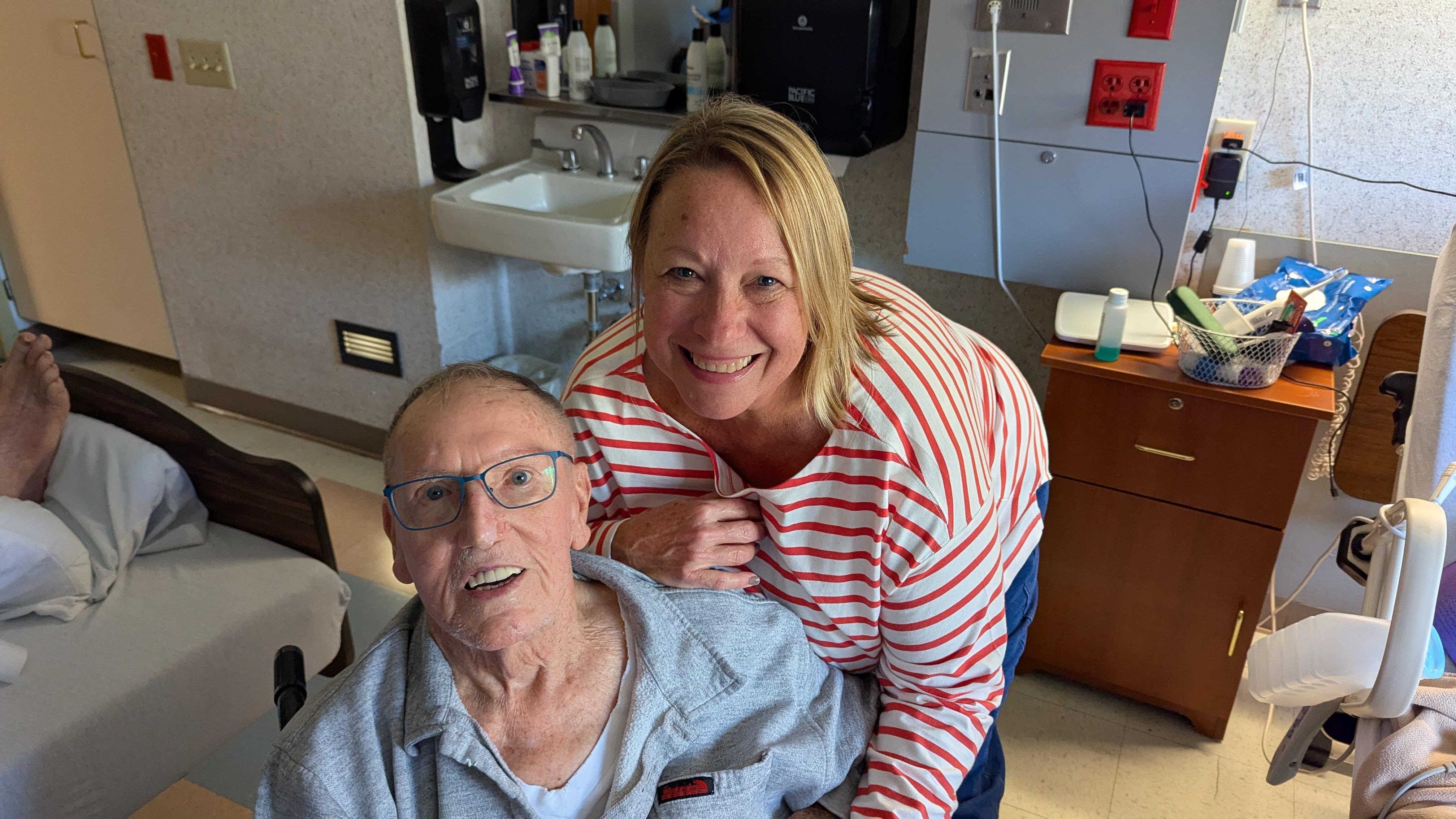 Two people are smiling together in a care facility.