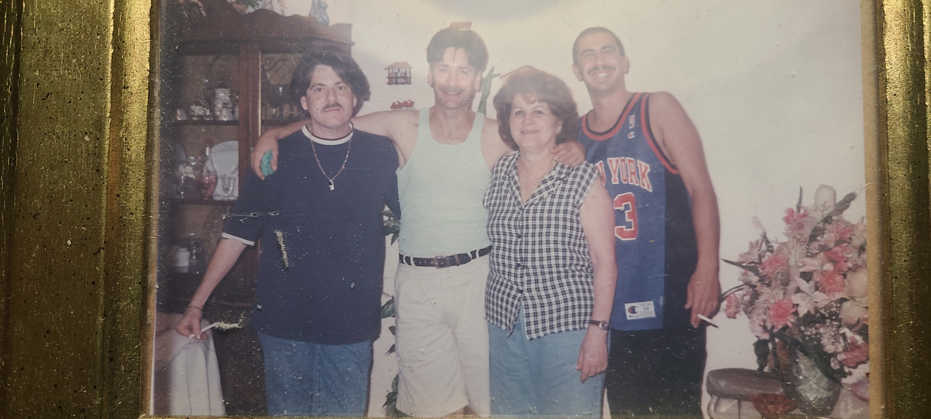 Four people stand together in a home setting, smiling and enjoying each other's company.