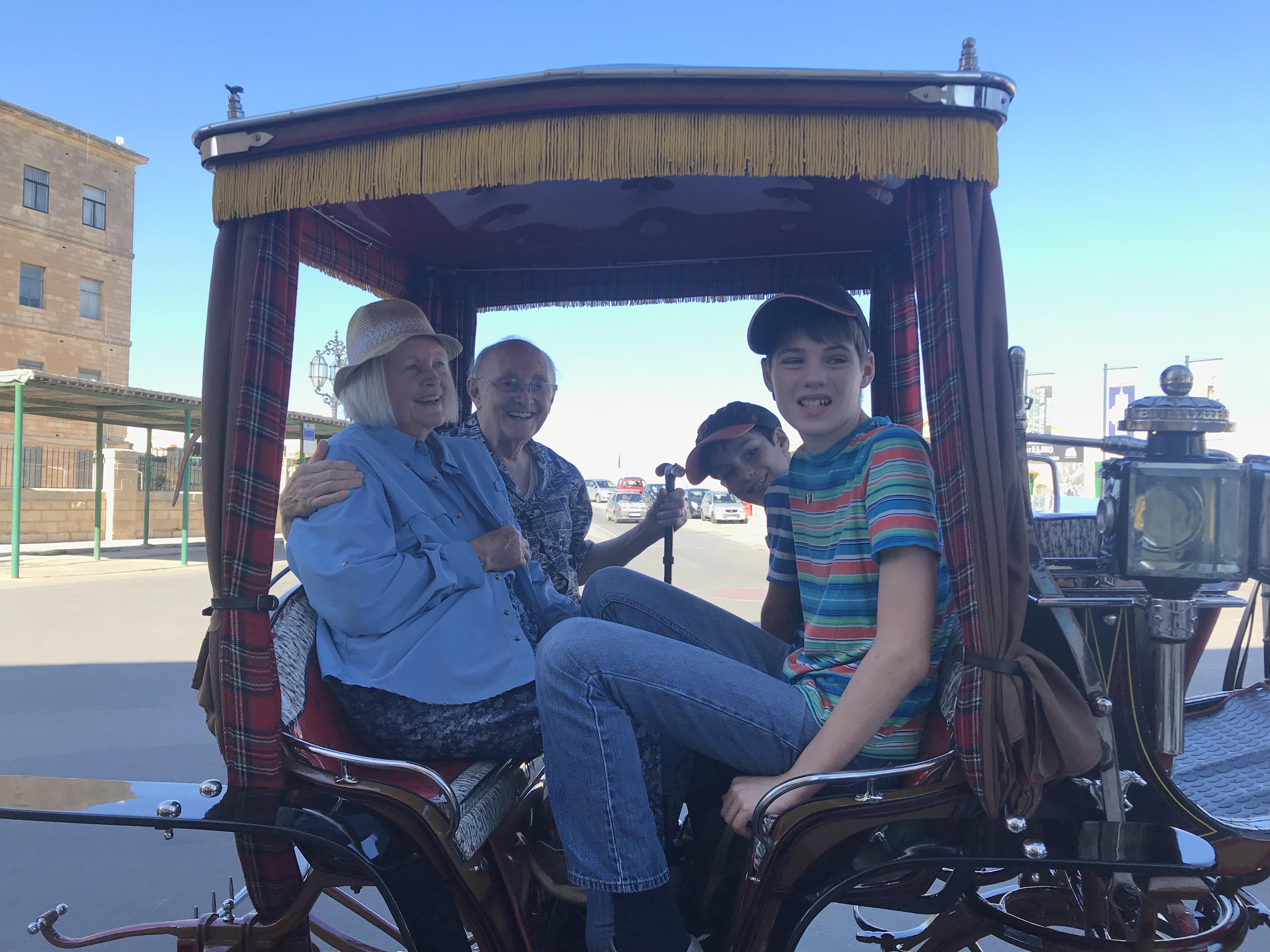 Four people smile while sitting together in a rickshaw. They enjoy their time in the city.