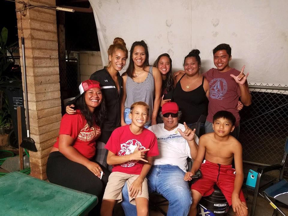 People are posing happily together in a home setting with casual clothes and smiles.