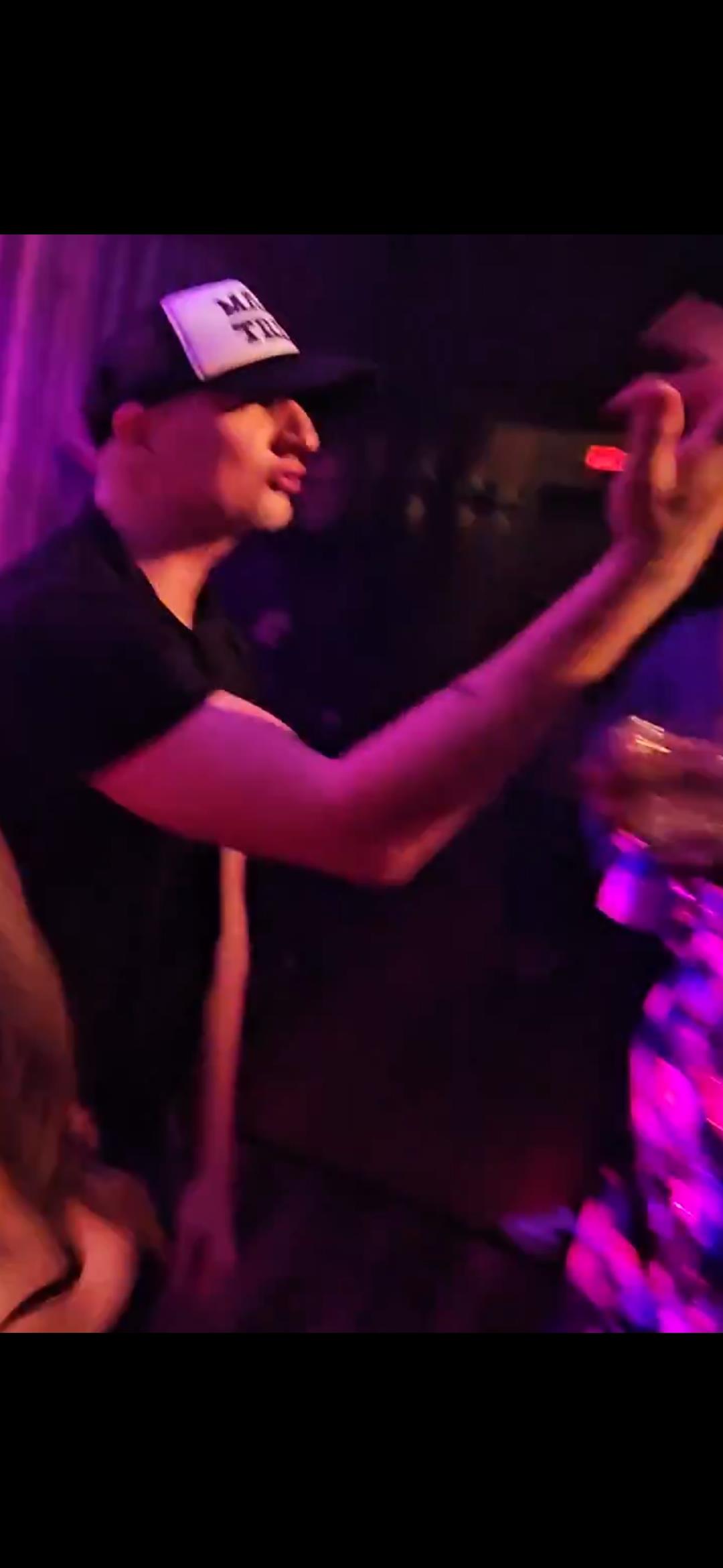 A person moves their hand in the air while dancing at a club during a lively night out.