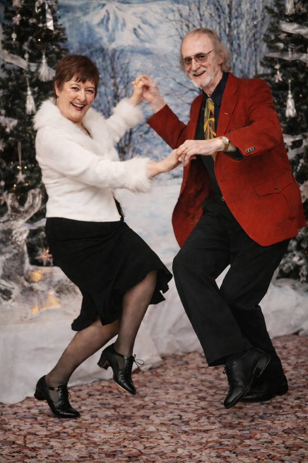 Two people are dancing joyfully at a holiday gathering with festive decorations around them.