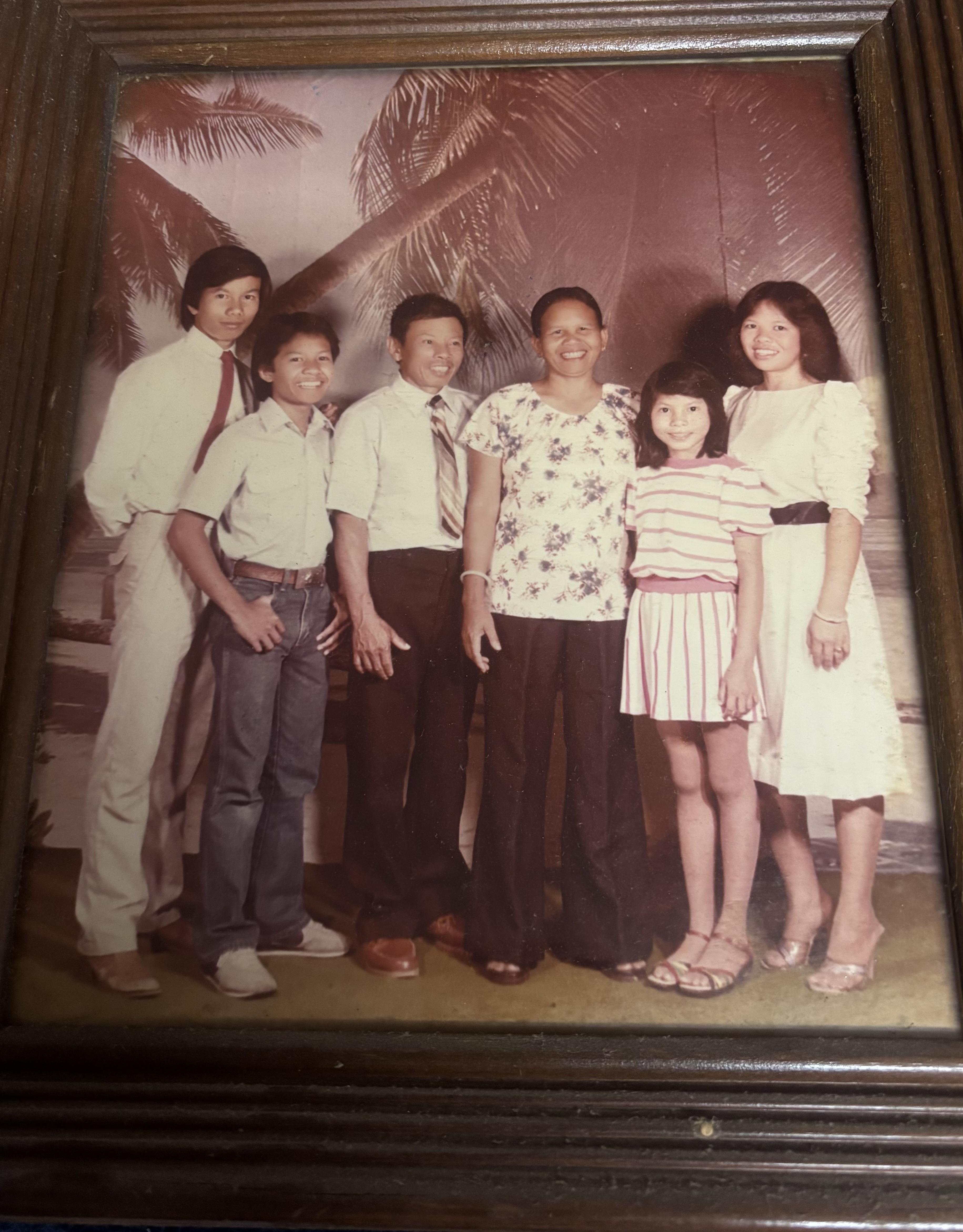 A group of six people is standing together in a studio setting. They are posing for a photo.