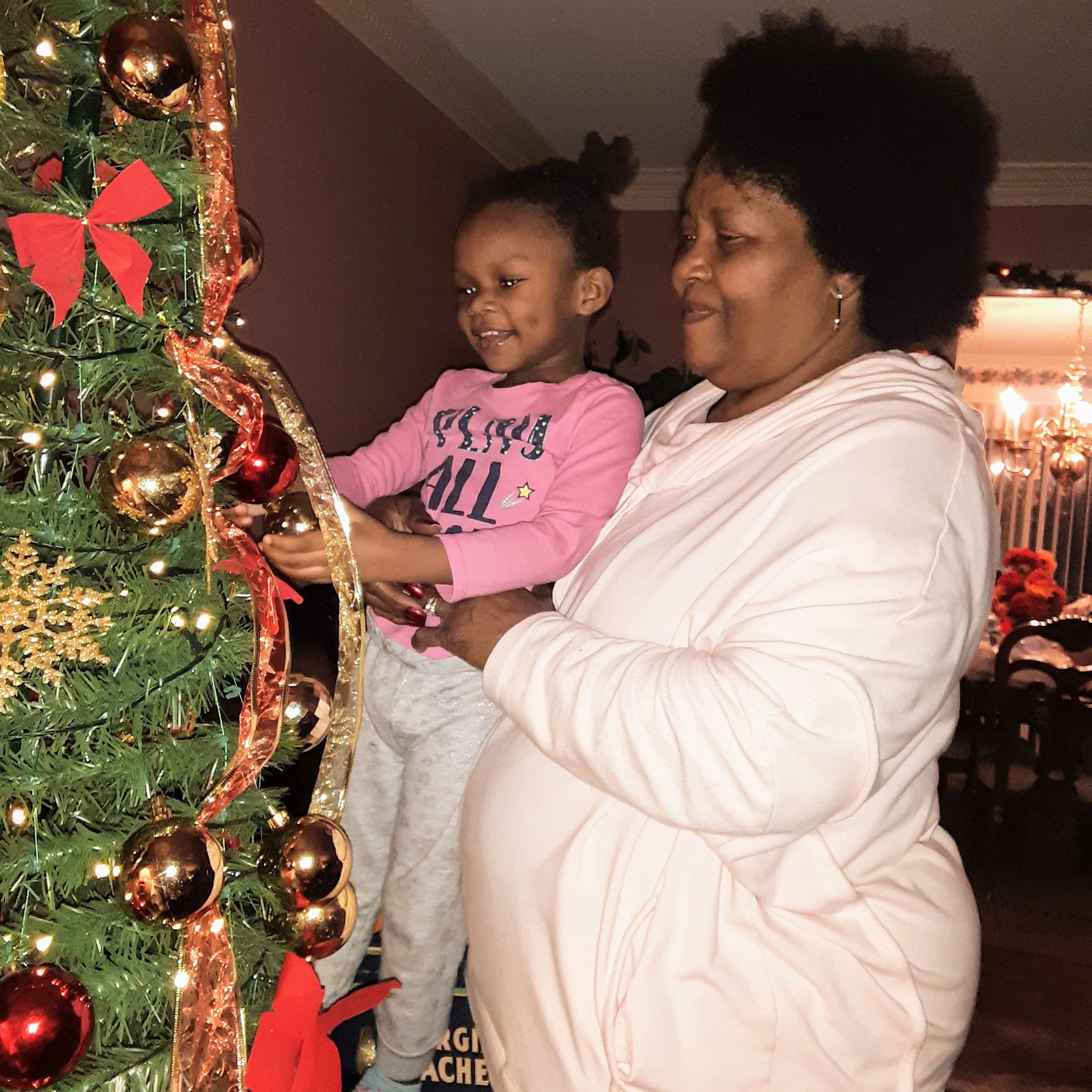 A woman and a child standing next to a christmas tree