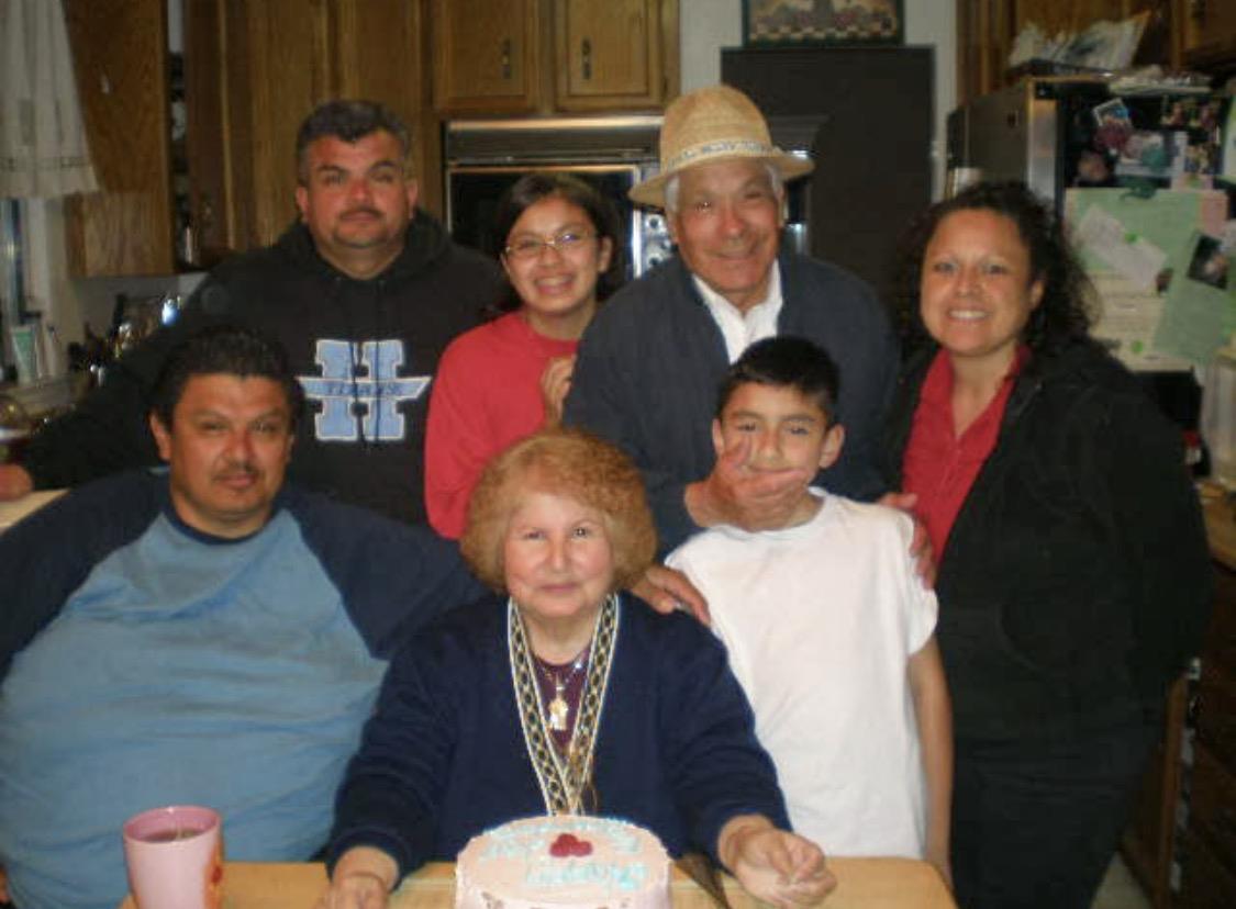 Family members celebrate a birthday together at home with a cake and happy faces.
