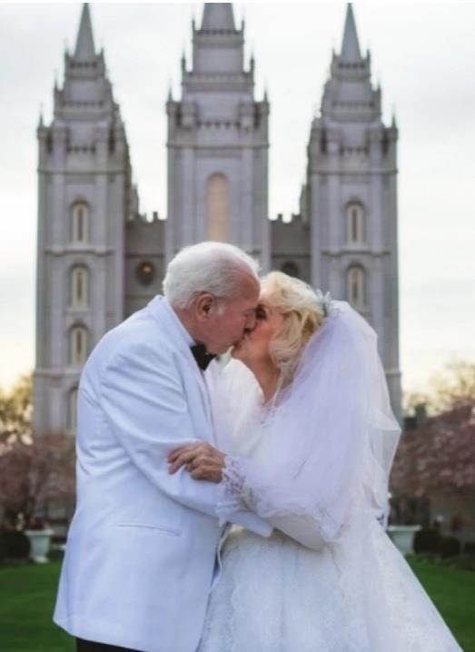 A man and woman kissing in front of a castle