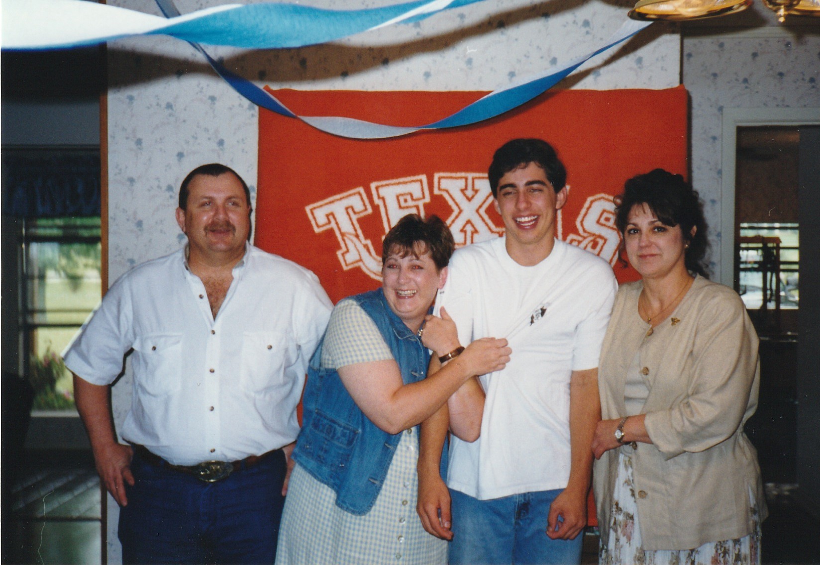 A group of four people gathered together in Texas celebrating an event with smiles and decorations.