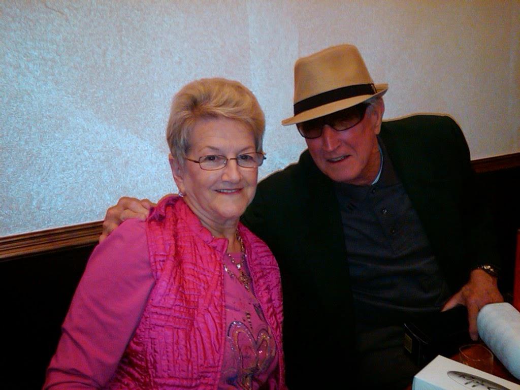 Two people sit close together at a table in a restaurant, smiling and enjoying time with each other.