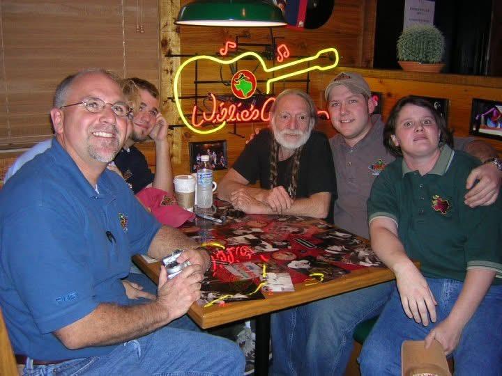 Friends gather around a table at Willie’s Cafe smiling and chatting after a long day.