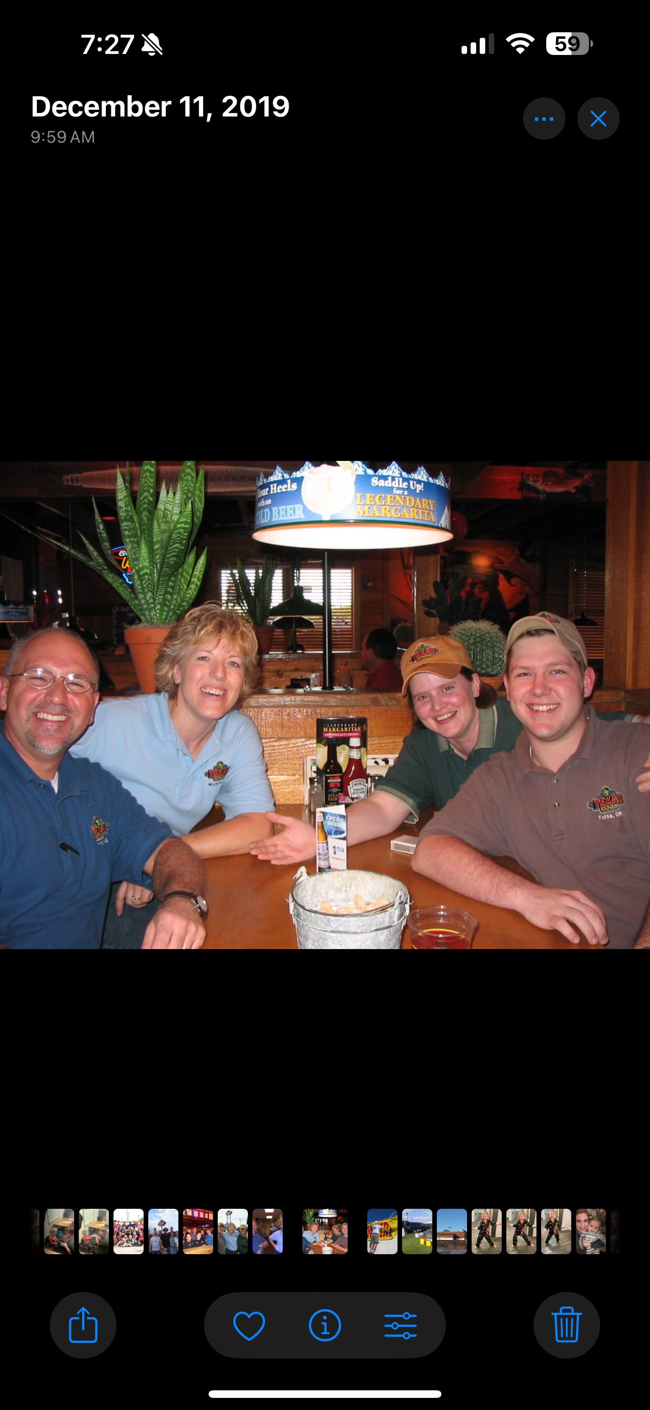 Four people sit at a table in a restaurant. They smile and interact while enjoying food.