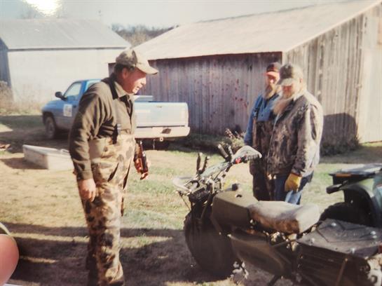 A group of men standing next to a motorcycle