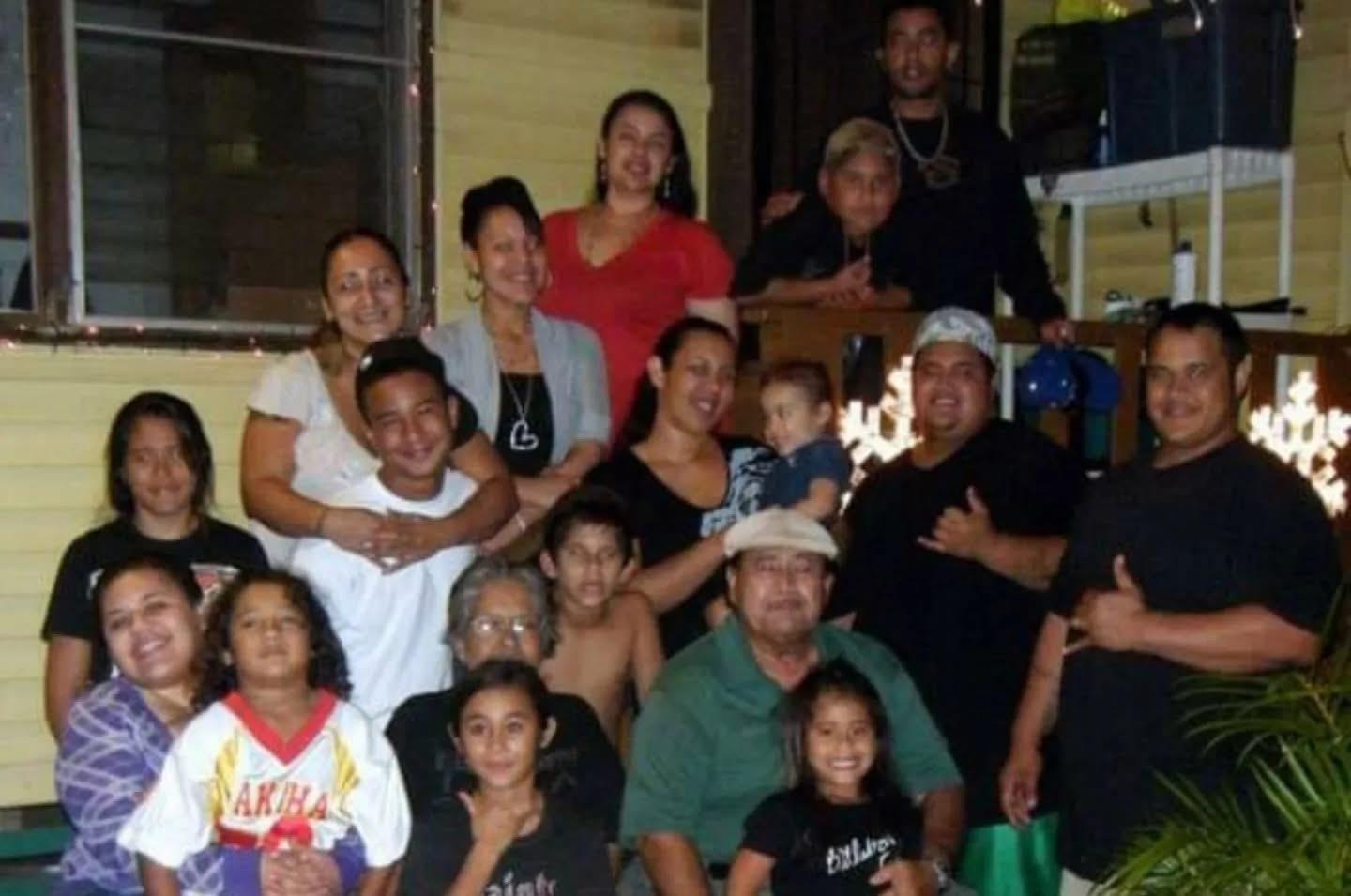 A large group of people poses together in a house for a celebration. Family members smile.