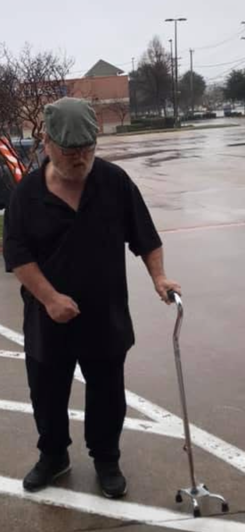 A man in a hat and black shirt holding a cane