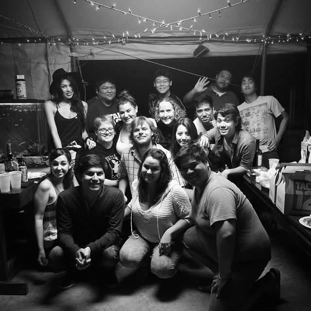 People are having fun together at a gathering with drinks and smiles in a tent at night.