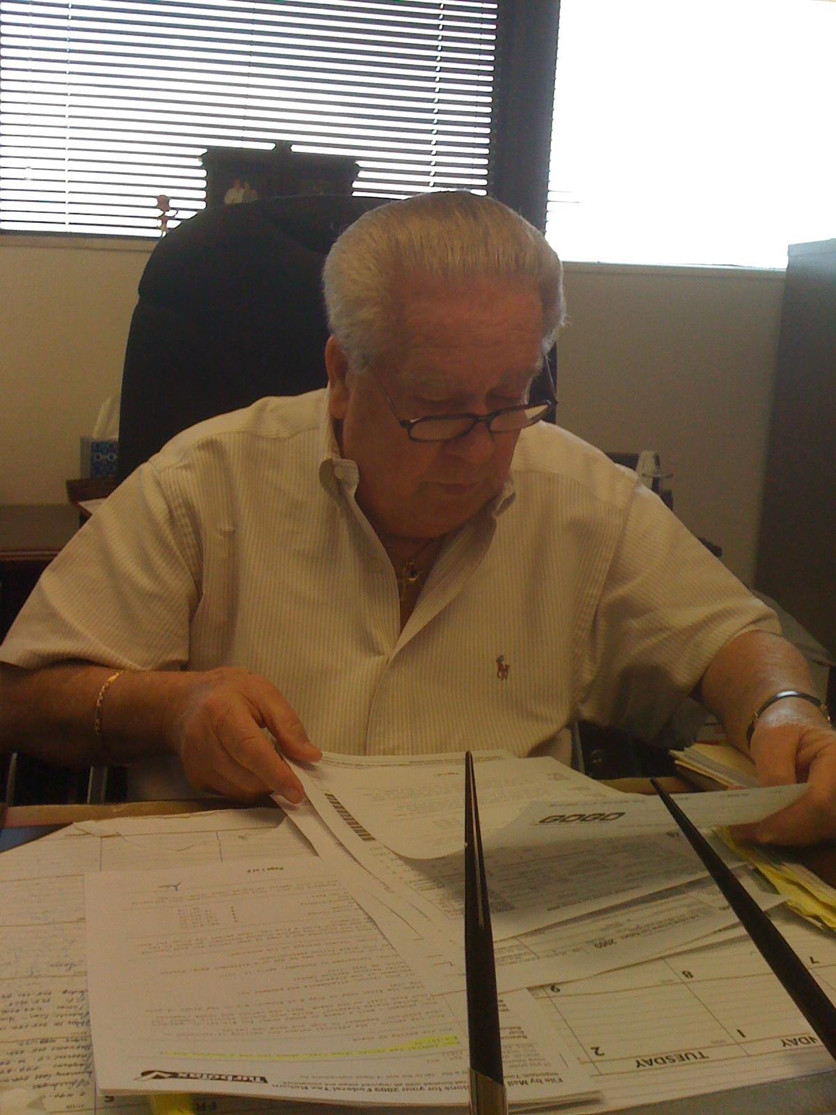 A man is focused on reviewing documents while sitting at a desk in an office.