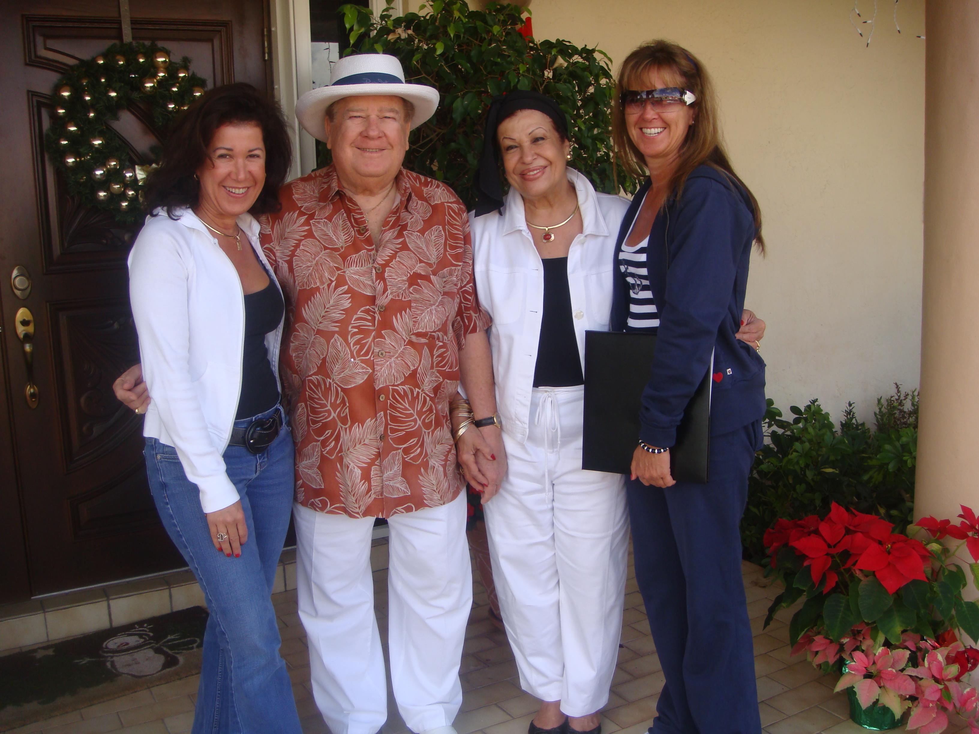 Four individuals gather outside a house. They smile and pose for a picture in the garden.